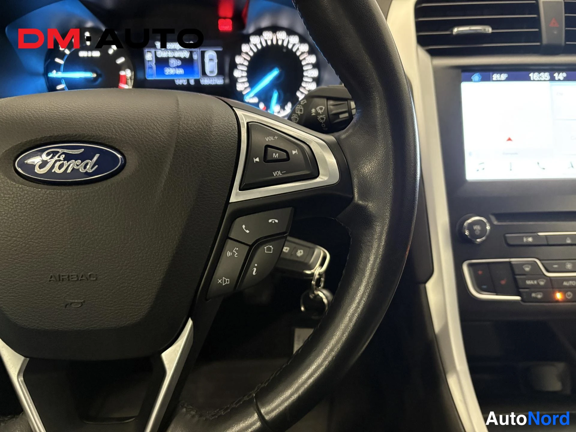 Yksityiskohta: Sisäkuva: ohjauspyörä Ford-merkillä ja AIRBAG-tekstillä,mittaristo ja multimedianäyttö taustalla.