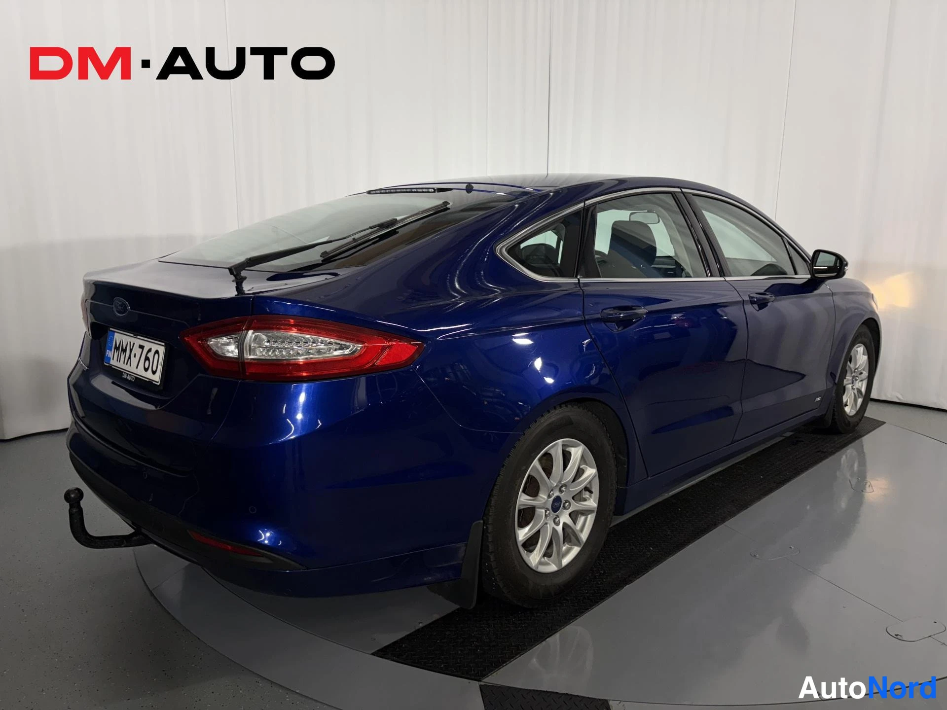 Takaviisto: Sininen Ford Mondeo -poro-auto takaa vasemmalta sivulta kuvattuna; takavalojen ja rekisterikilven lisäksi näkyvällä sivulla vasemmat ovenkahvat, vasen takapyörä