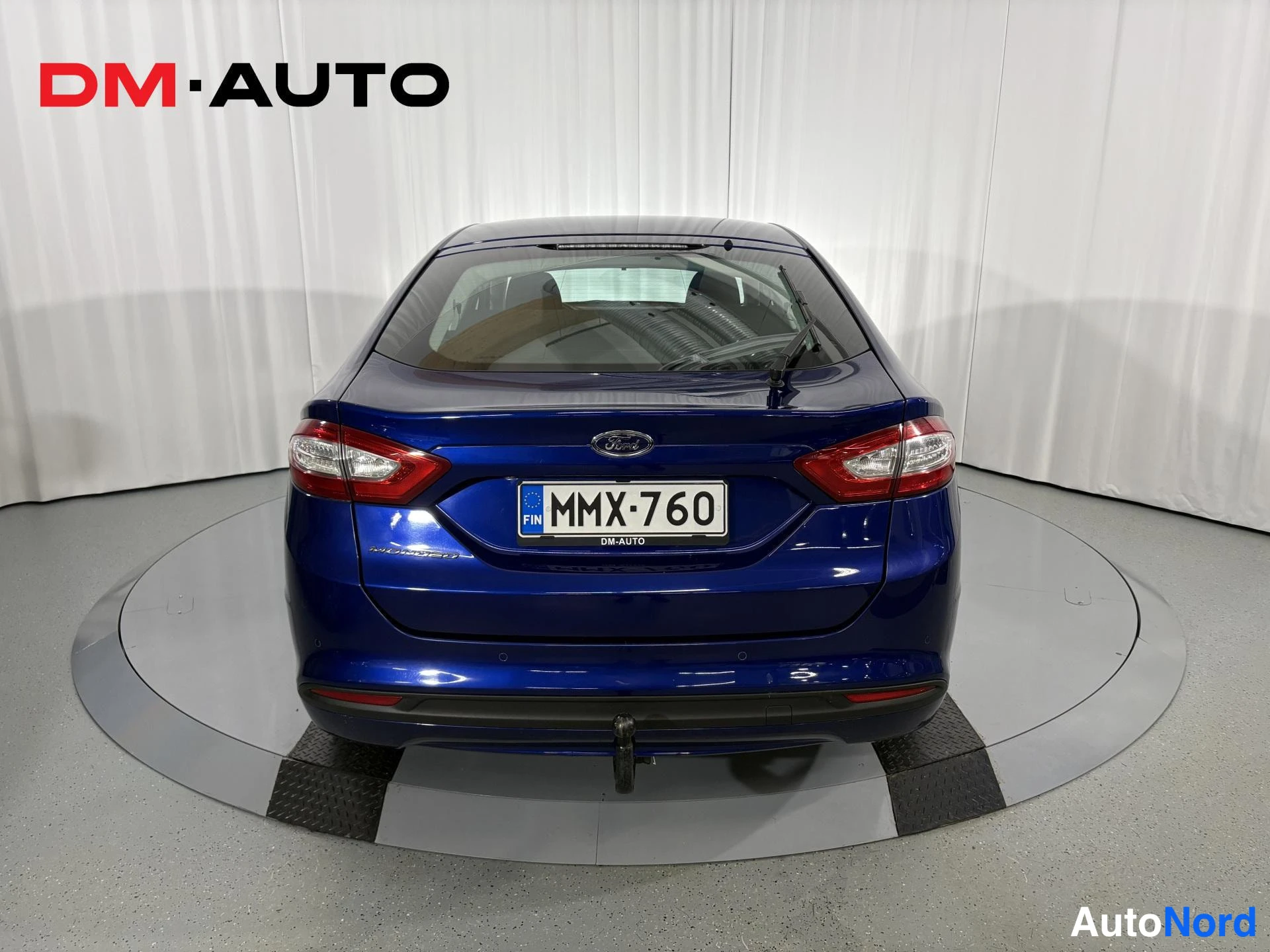 Takaa: Sininen Ford Mondeo suoraan takaa kuvattuna; takavalaistus, Ford-merkki, rekisterikilpi ja irrotettava tähkä näkyvät.