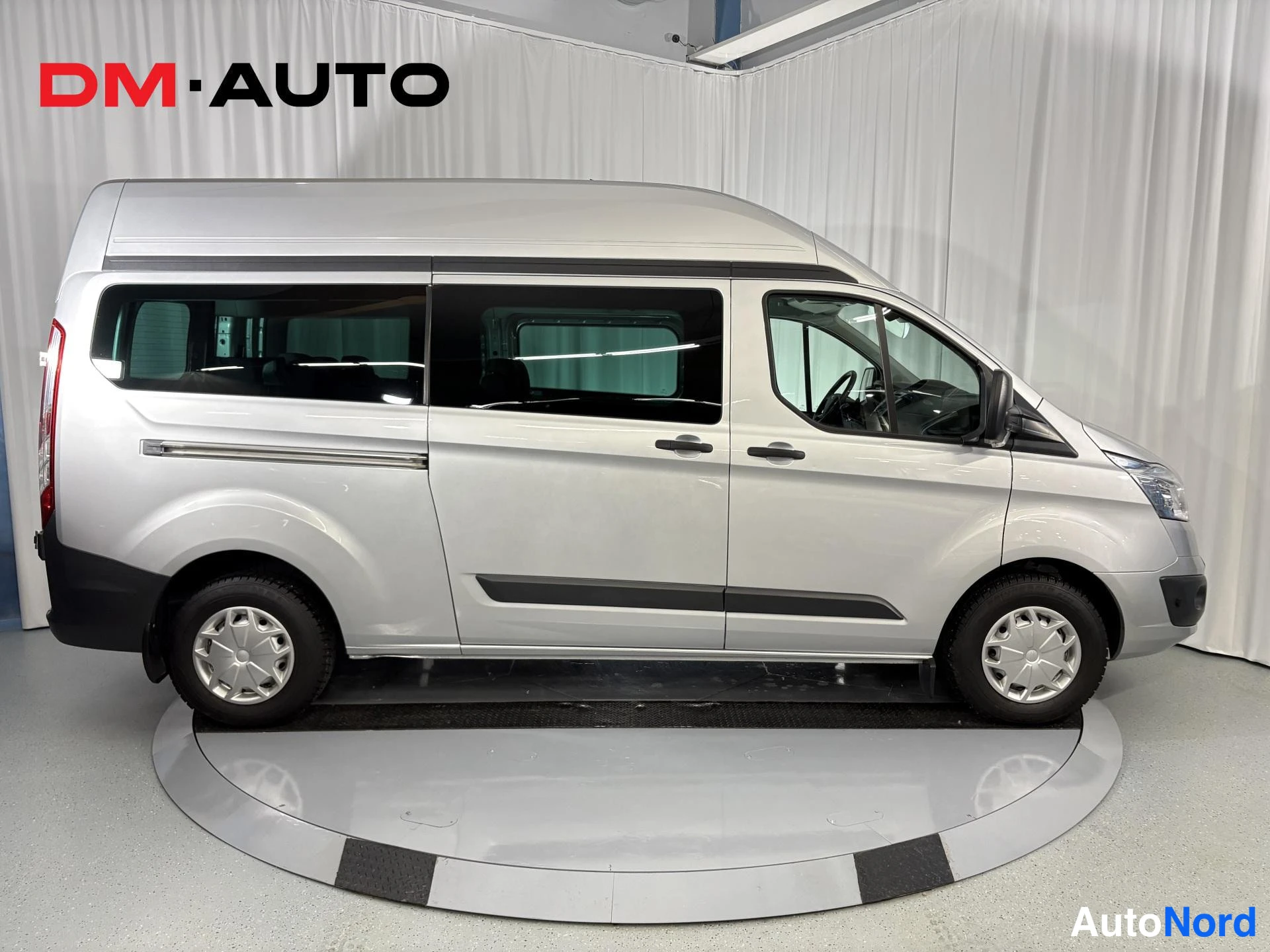 Etuviisto, nokka oikealle: Hopeanharmaan Ford Transit Custom -pakettiauton oikean sivun näkymä, jossa näkyvät neljä ovea ja tummat ikkunat.
