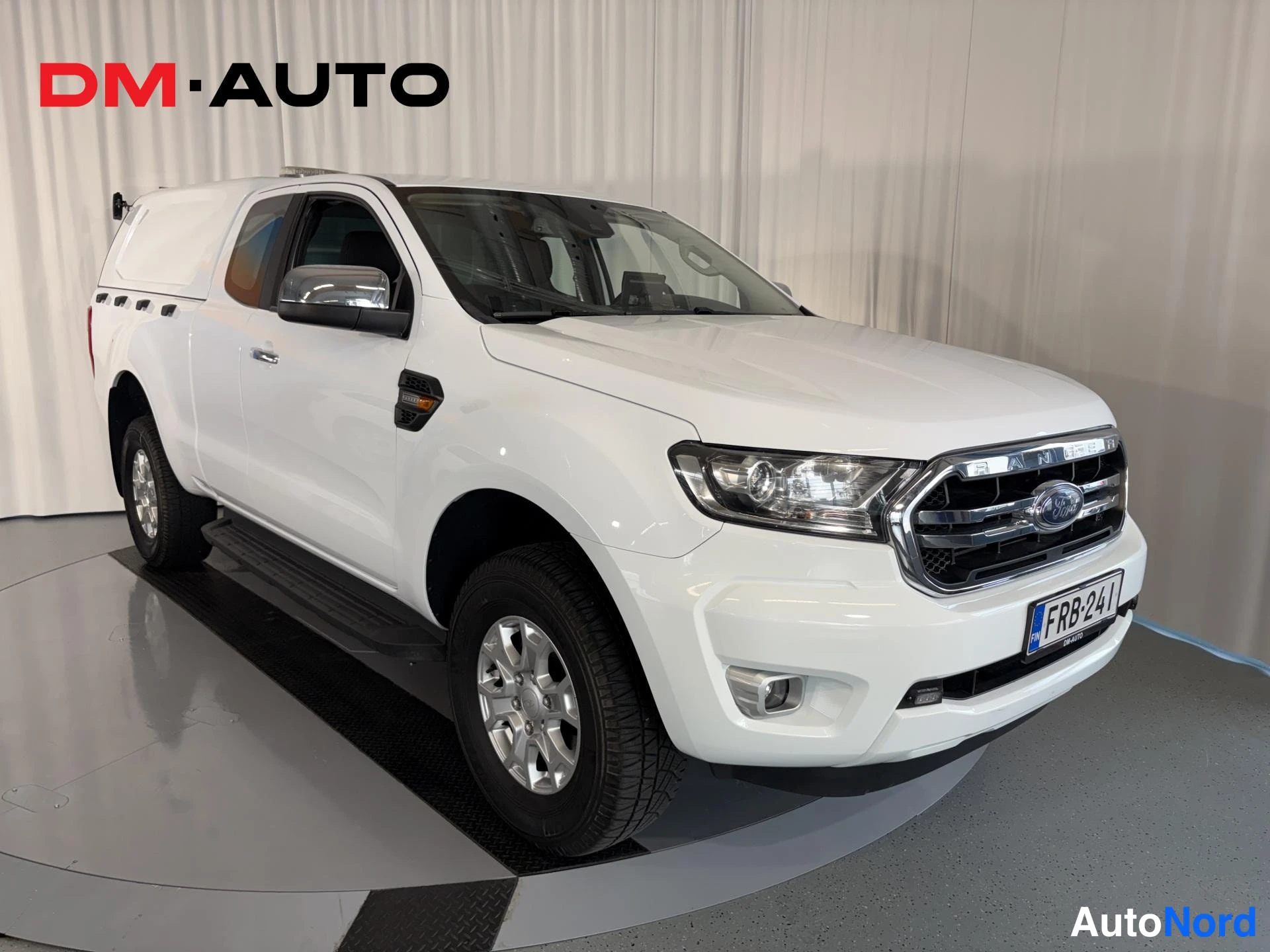 Etuviisto, nokka oikealle: Valkoinen Ford Ranger -pakettiauto etuosalta ja oikealta sivulta, NIL-alueella oleva rekisterikilpi.