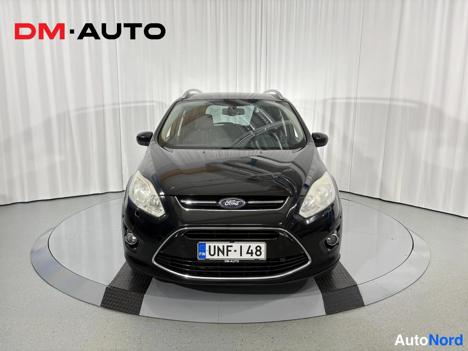Edestä: Mustan Ford C-MAX -tilavaunun suora etukuva, keulagrilli, Ford-merkki ja etuvalot näkyvissä.