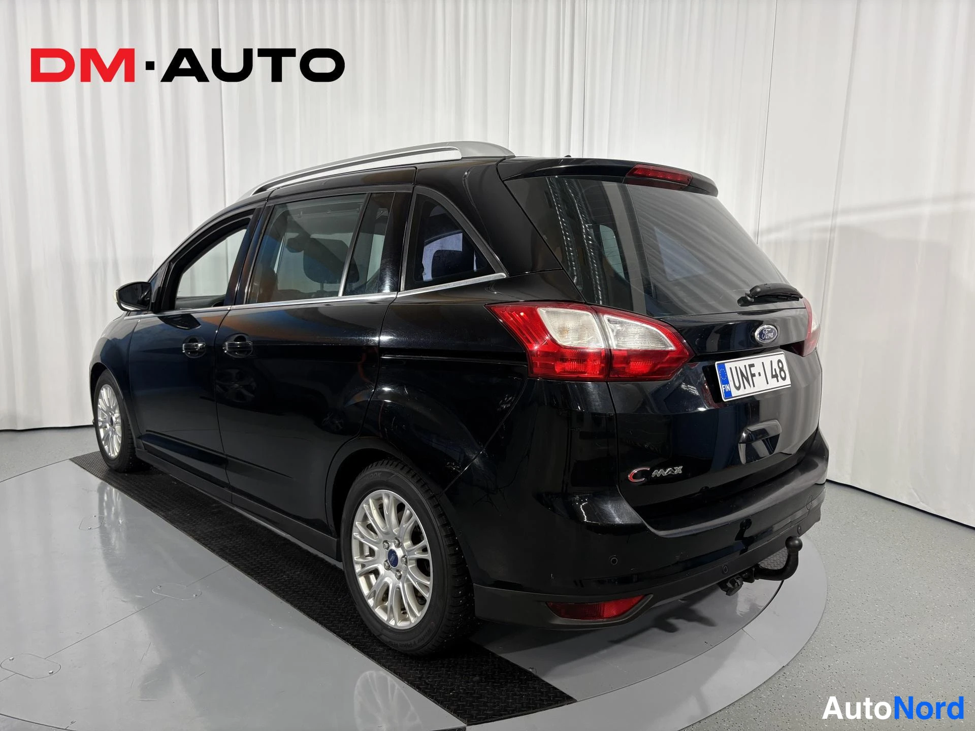 Takaviisto: Musta Ford Grand C-MAX takaviistosta vasemmalta, takavalot, C-MAX-merkki, kattokaiteet ja rekisteritunnus näkyvissä.