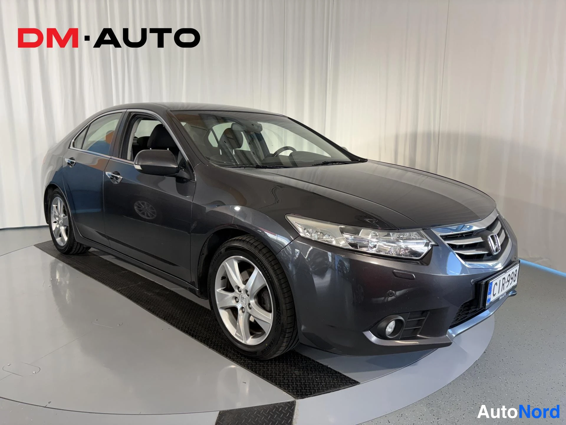 Etuviisto, nokka oikealle: Tummanharmaa Honda Accord -sedan etukulmasta oikealta, kilpi ja hopeavanteet näkyvissä.