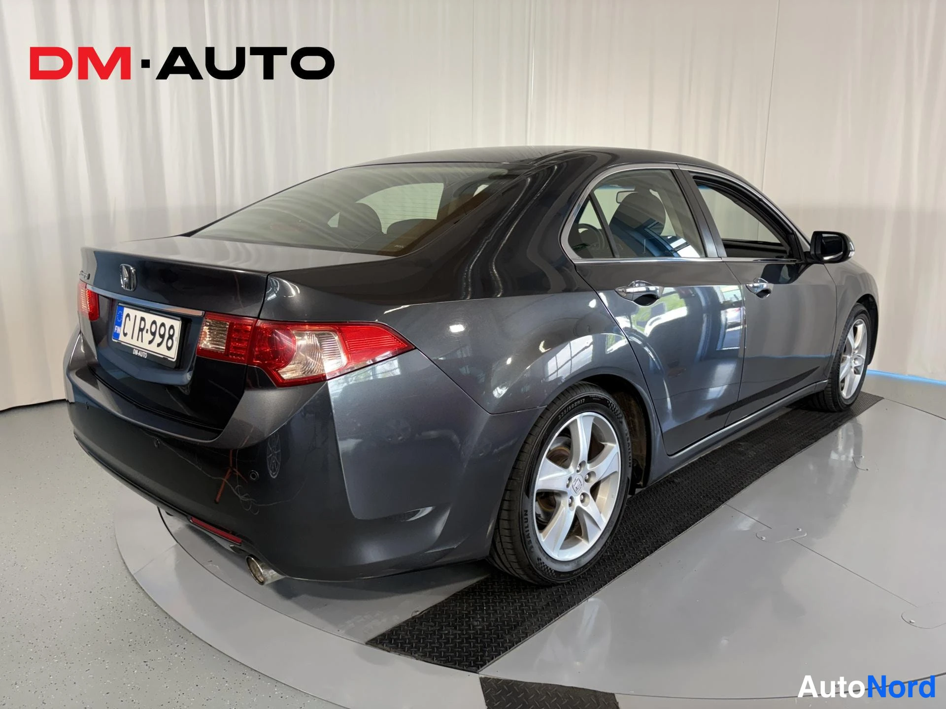 Takaviisto: Taka-kolmasosakuva tummanharmaasta Honda Accord -sedanista näkyvissä takaosassa, vasen kylki ja rekisteritunnus.