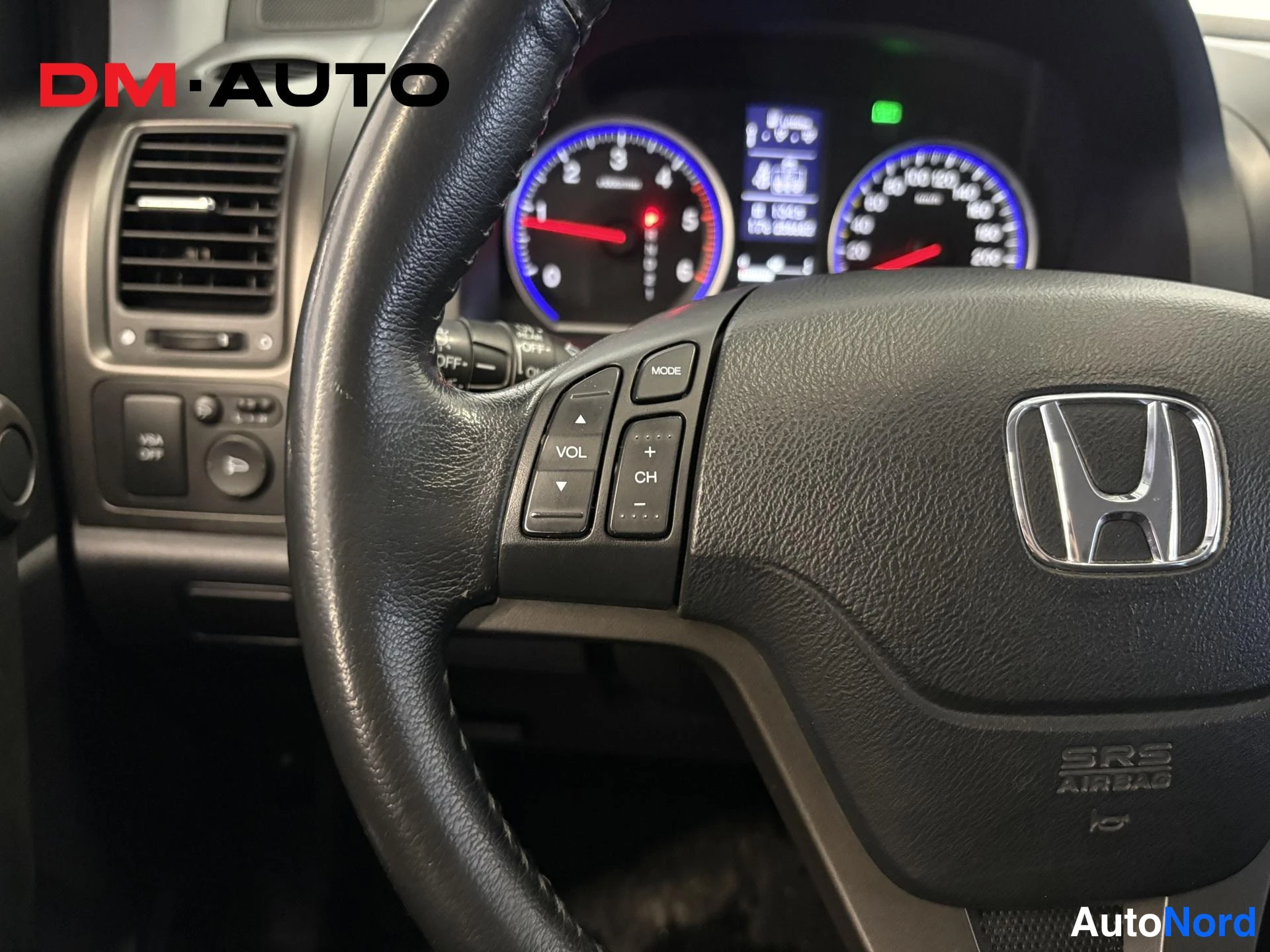 Muu: Lähikuva Honda CR-V:n ohjauspyörän vasemmasta kytkinpaneelista, jossa painikkeet MODE, VOL, +CH, ja SRS AIRBAG-teksti ohjauspyörän navassa.