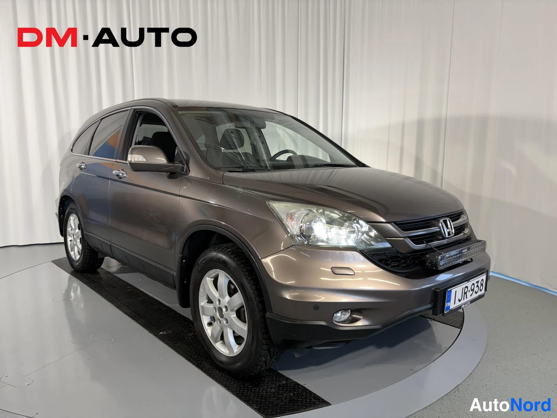 Etuviisto, nokka oikealle: Honda CR-V etuviistosta oikealta, ruskeaharmaa koripinta, rekisteritunnus JR-938.