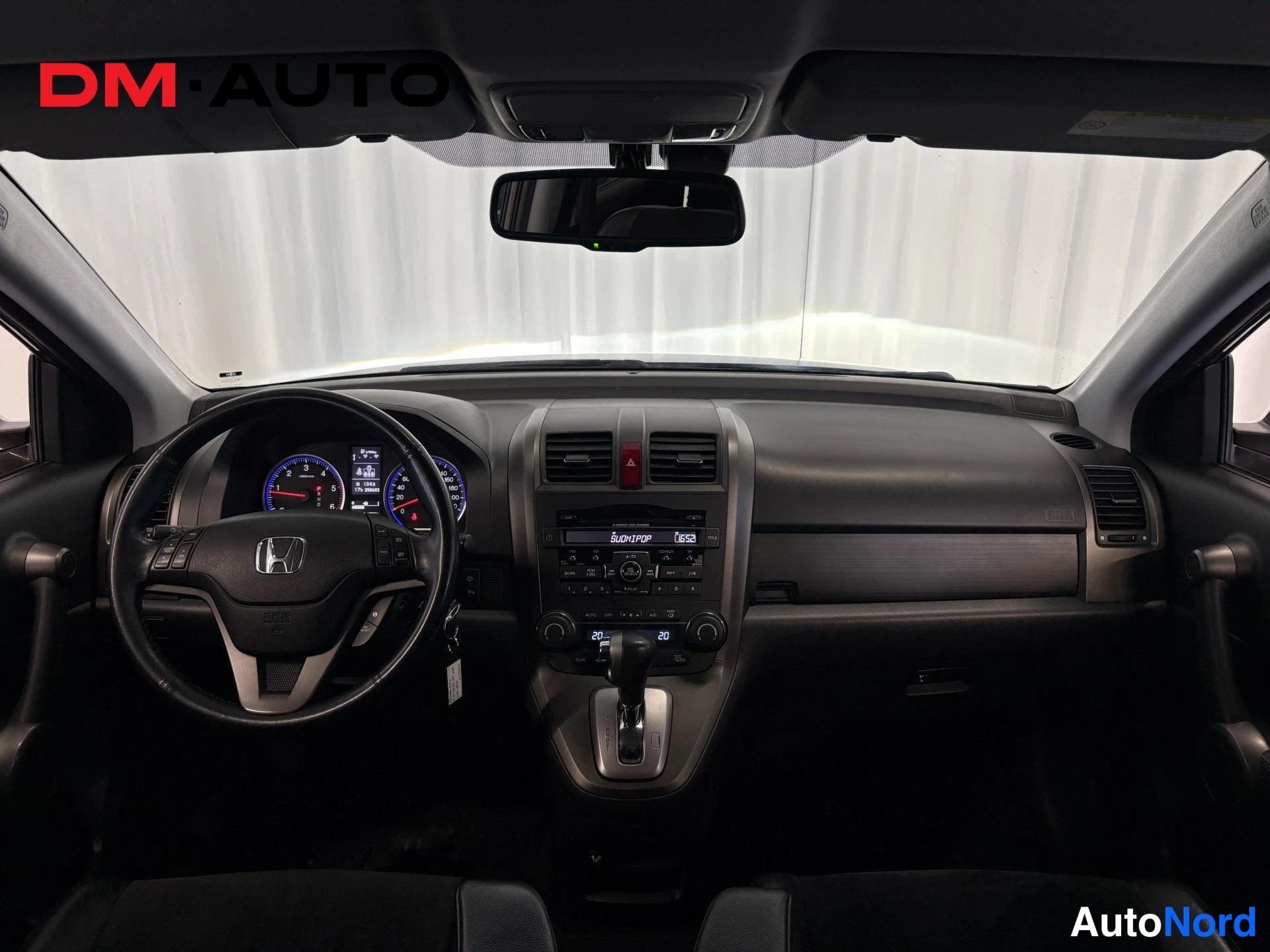 Muu: Honda CR-V:n ohjaamo kuvattuna kojelaudan yli: Honda-ohjauspyörä, analoginen mittaristo, keskikonsolin radio- ja ilmastointilaitteet, joiden näytöissä lukee 'Su