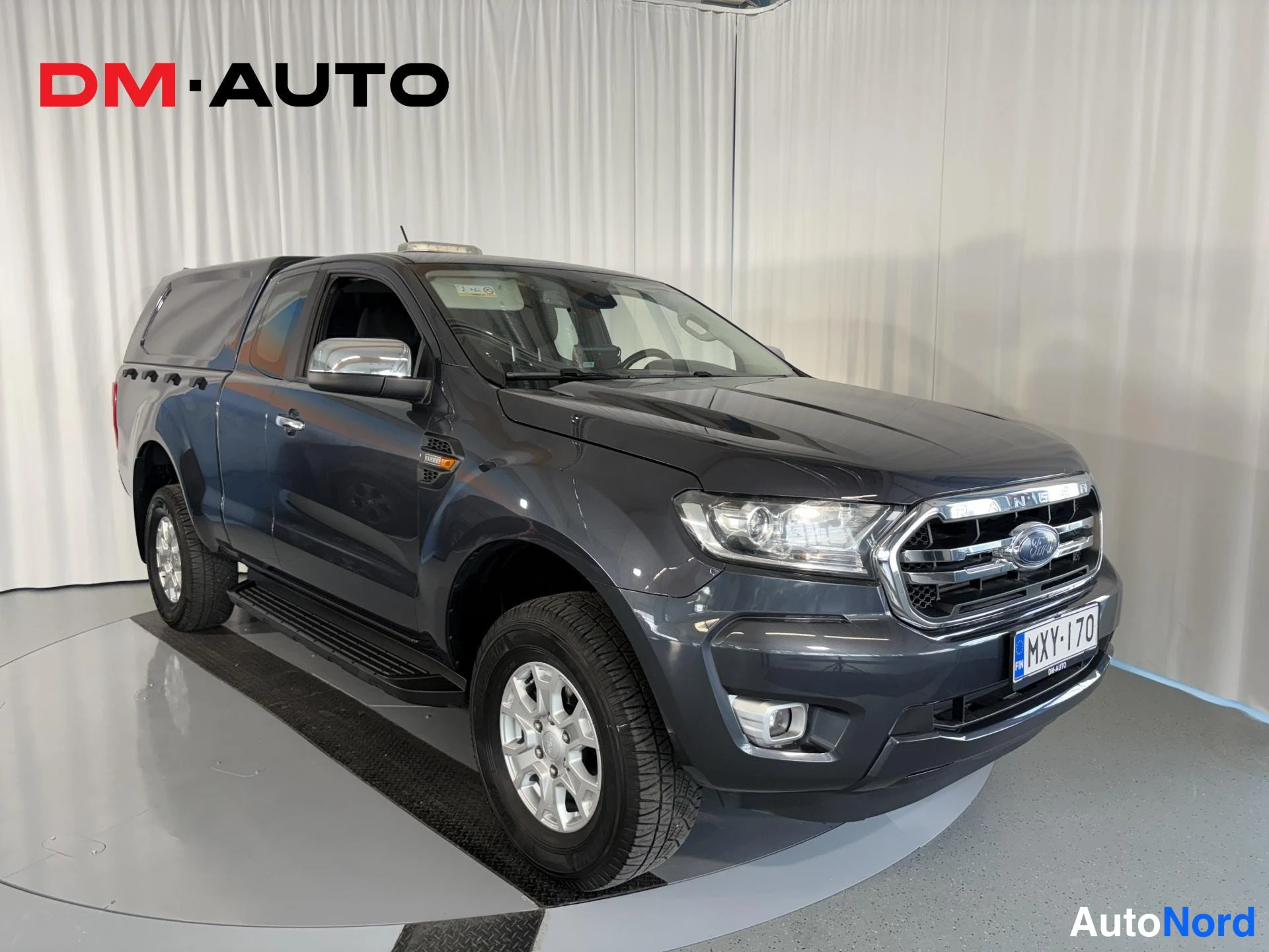Etuviisto, nokka oikealle: Tummanharmaa Ford Ranger -avaustakavara, etukolmivasoisto oikealle; etusäleikkö ja kylki näkyvät, rekisterikilpi.