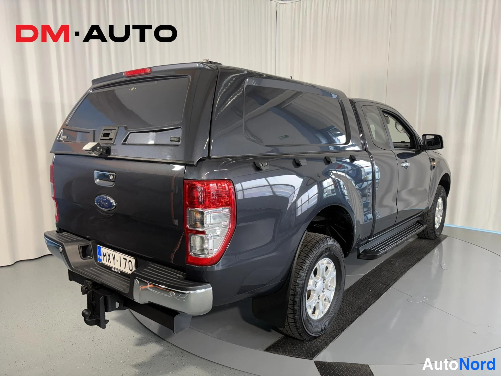 Takaviisto: Taka­kolmasosanäkymä tummanharmaasta Ford Ranger -avolavasta; näkyvät takavalot, Ford-merkki, rekisterikilpi, kylkijalka ja vetokoukku.