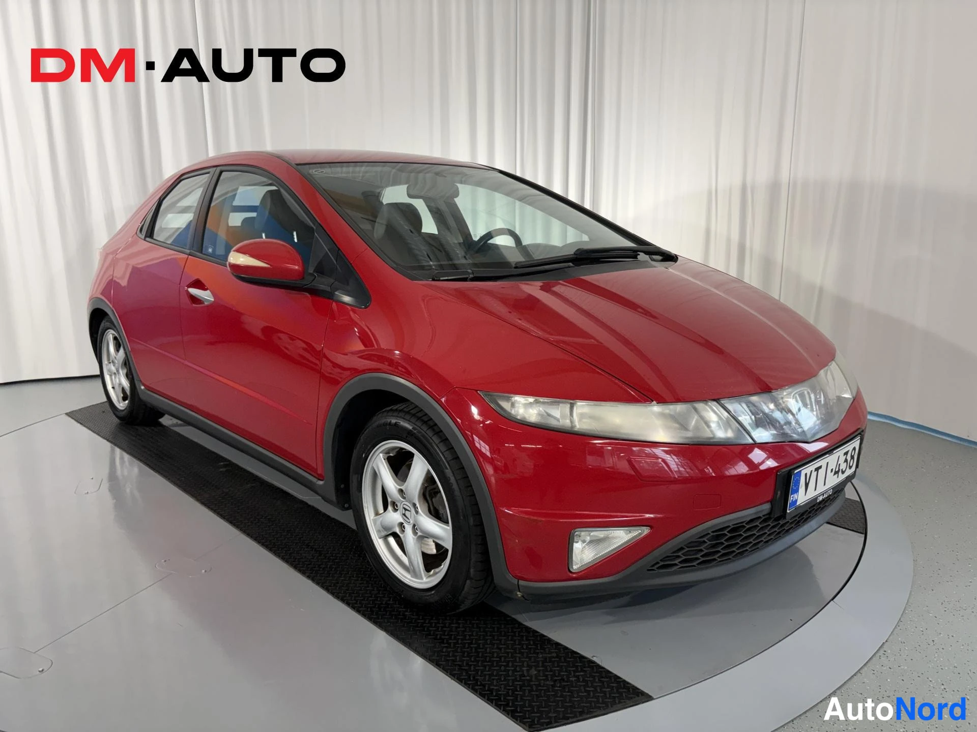 Etuviisto, nokka oikealle: Punaisen Honda Civicin etunurkkakuva oikealta, hopeavanteet ja rekisterikilpi VT·438 näkyvät.