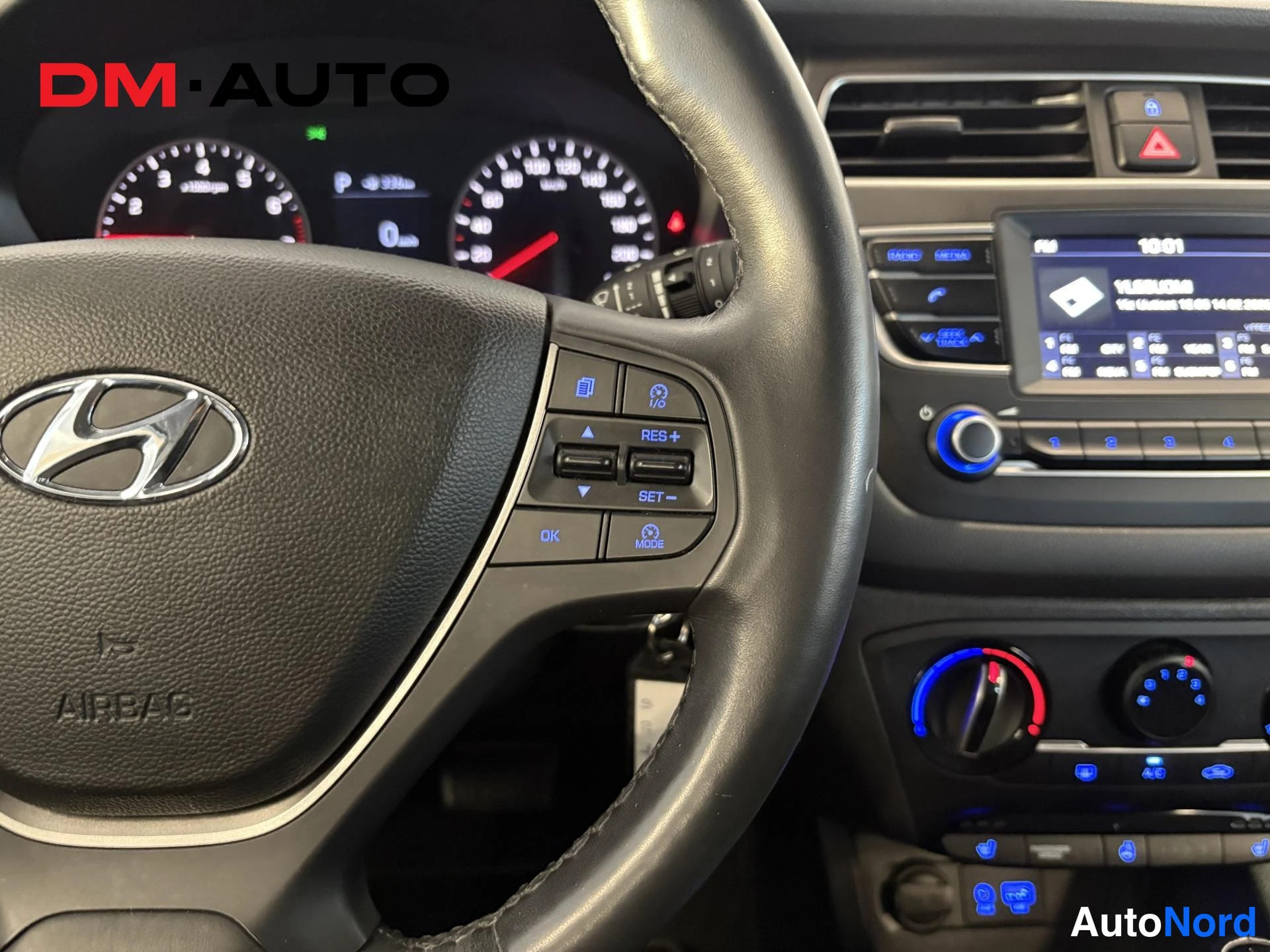 Muu: Ohjaamon lähikuva: Hyundai-merkkiohjauspyörä, infotainment-näyttö ja hallintanapit, taustassa mittaristo.