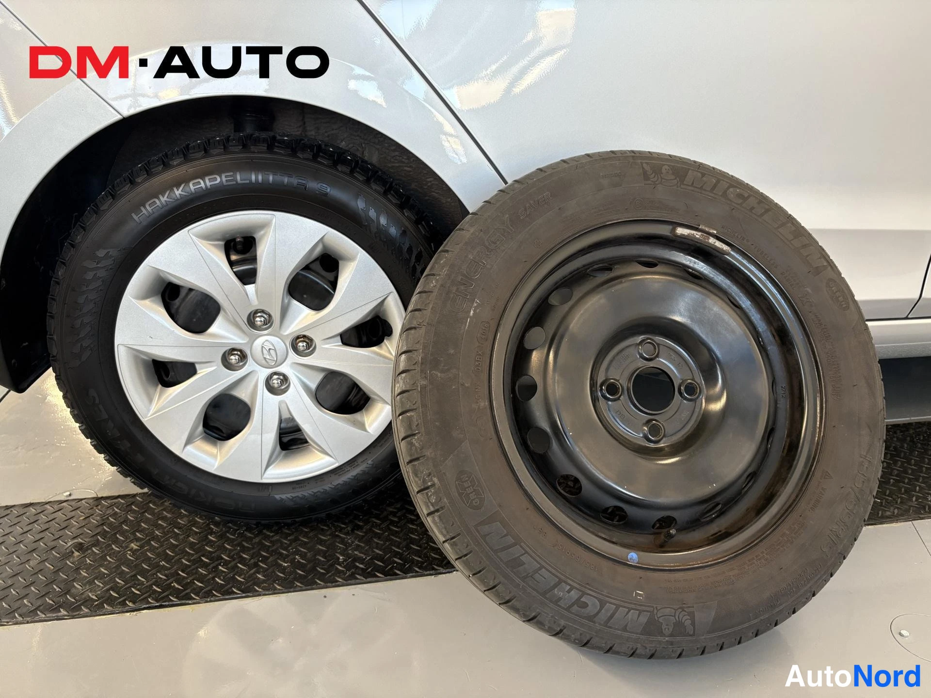 Muu: Renkaanvaihto: autoon asennettu talvirengas Nokian Hakkaapeliitta 9 alumiinivanteella ja vieressä varaovan kaltainen teräsvanteella oleva kesärengas Michelin En