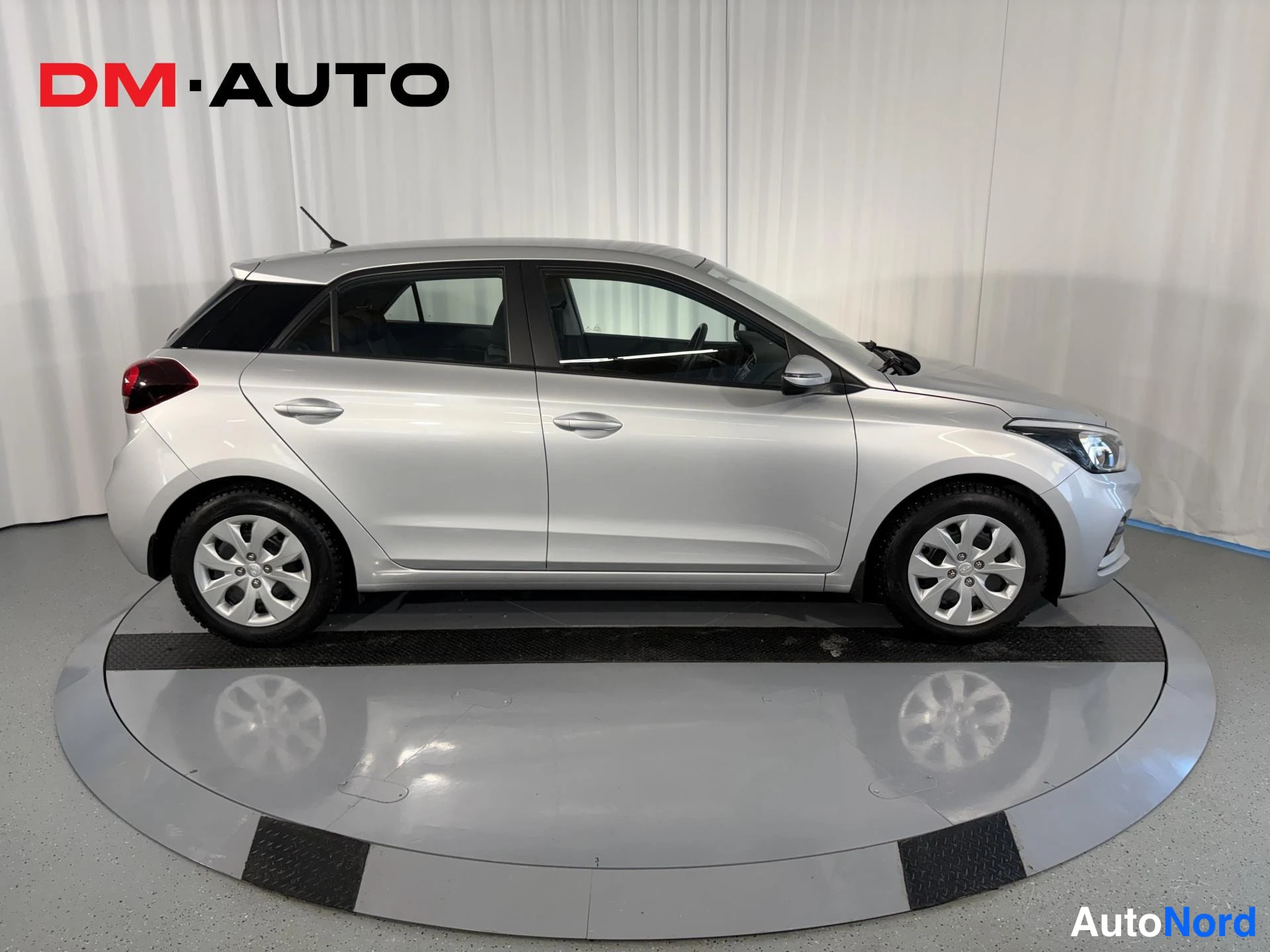 Sivulta: Hopeanvärinen Hyundai i20 sivusta oikealta, ovien ja pyörien profiili näkyvissä.