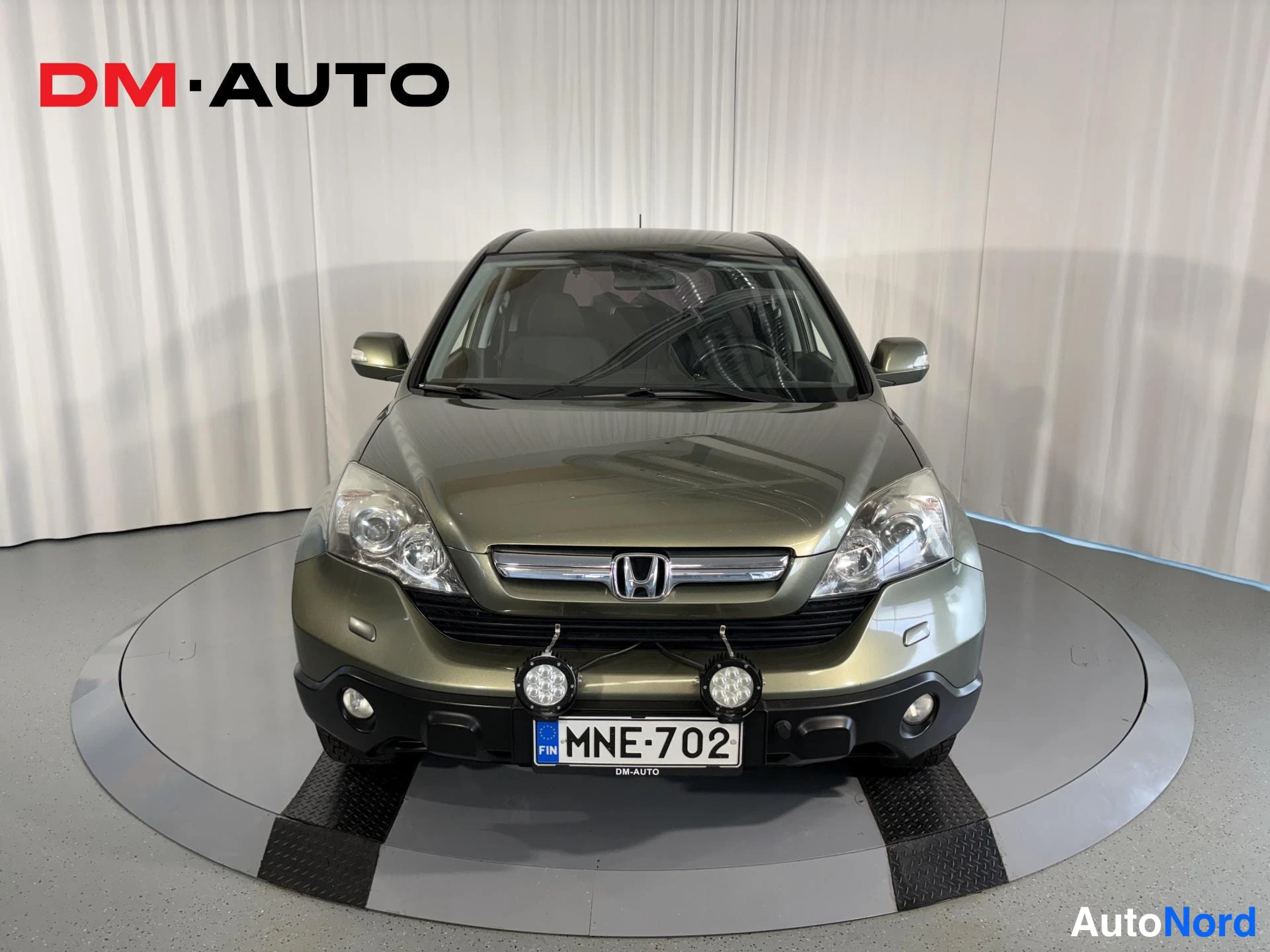 Edestä: Honda CR-V suoraan edestä, etusäleikkö, ajovalot ja rekisteritunnus näkyvissä, lisävalot puskurissa.
