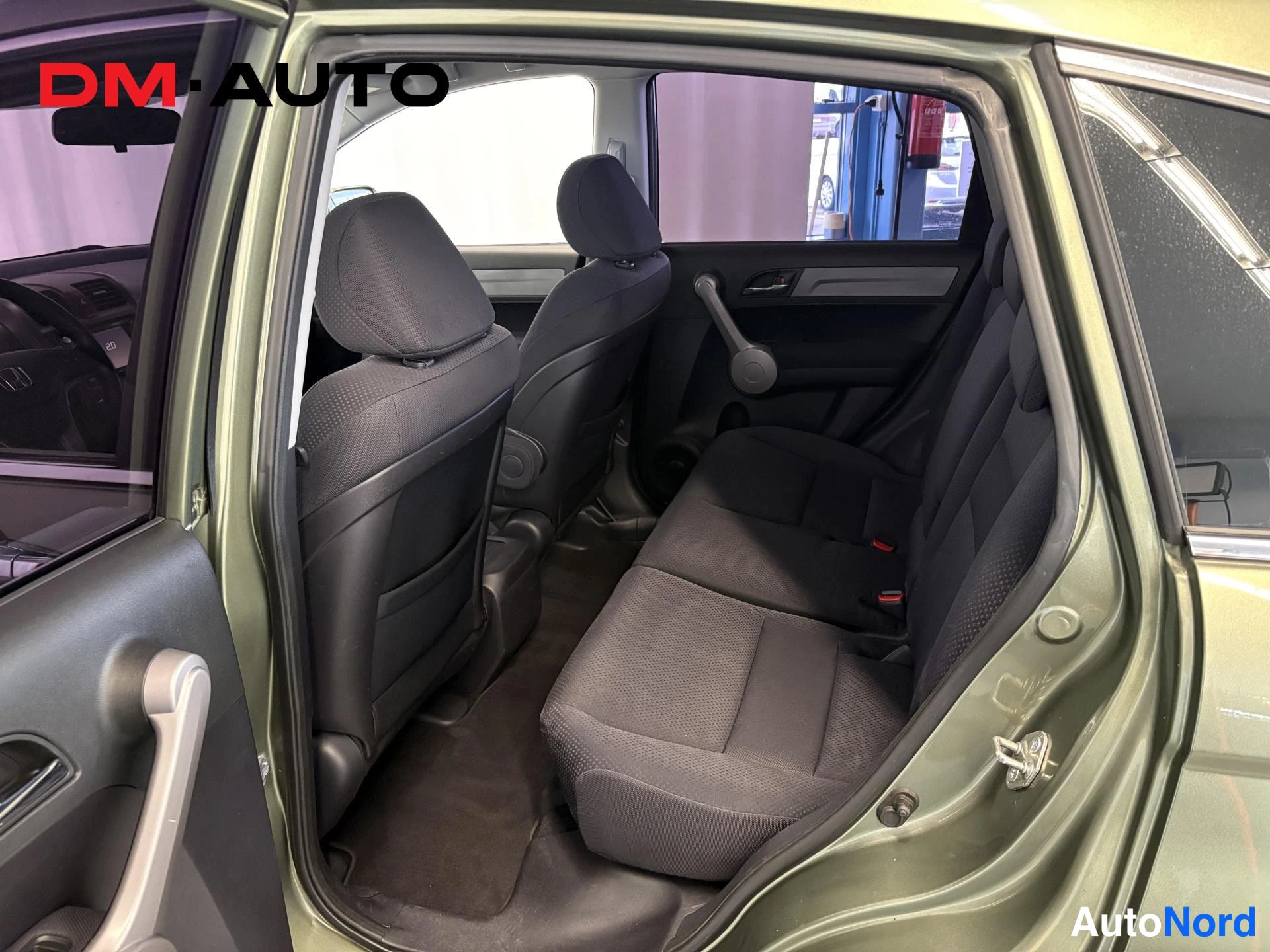 Muu: Honda CR-V:n takaistuimet ja avattu takaovi; tummia kangasistuimia ja mattoa lattiassa.