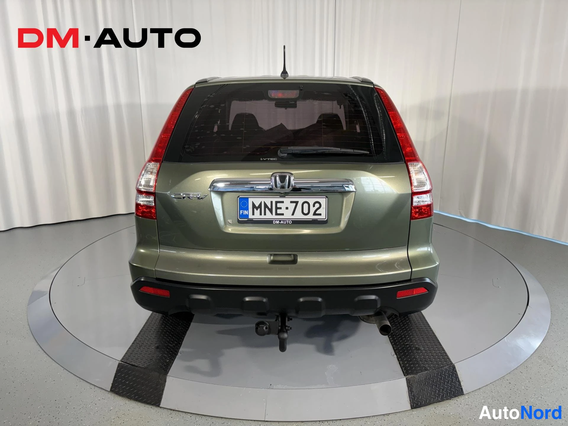 Takaa: Honda CR-V suoraan takaa kuvattuna, vihreä koriväri, rekisterikilpi, vetokoulu ja pakoputki näkyvissä.