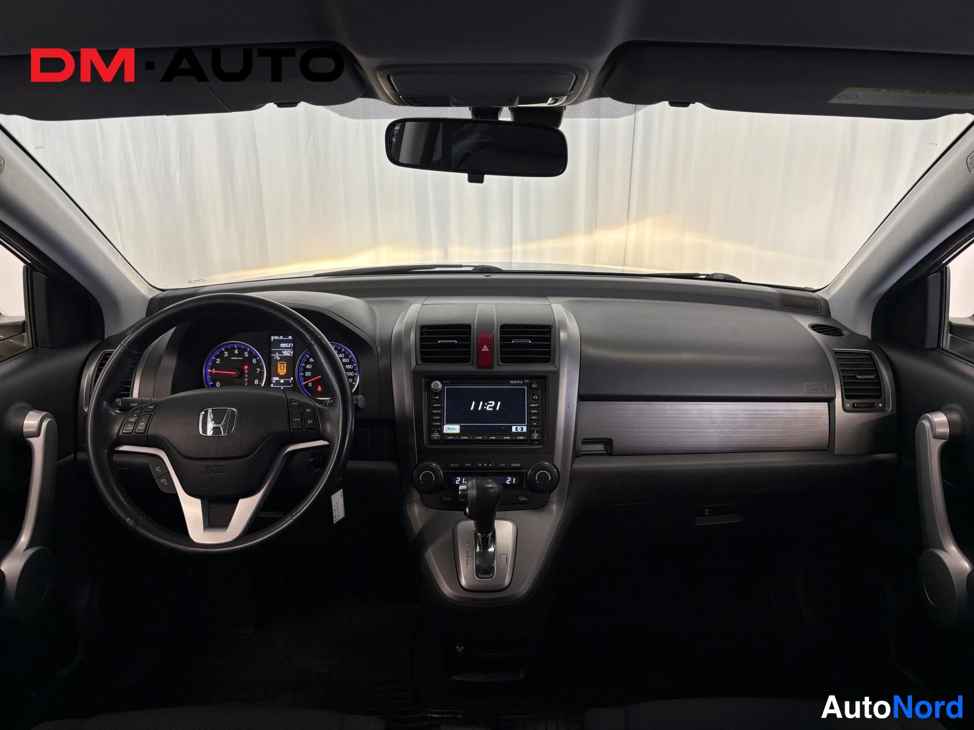 Muu: Honda CR-V:n ohjaamo tuulilasin läpi kuvattuna: ratto, kojelauta ja keskikonsoli, näytössä 11:21