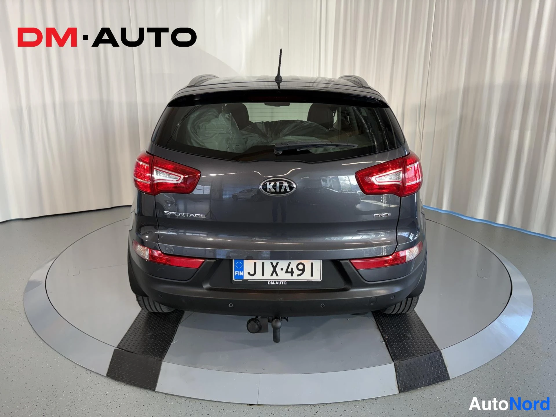 Takaa: Suora takanäkymä tummanharmaasta Kia Sportagesta: KIA-merkki, SPORTAGE- ja CRDi-tekstit, takalasi ja rekisterikilpi.