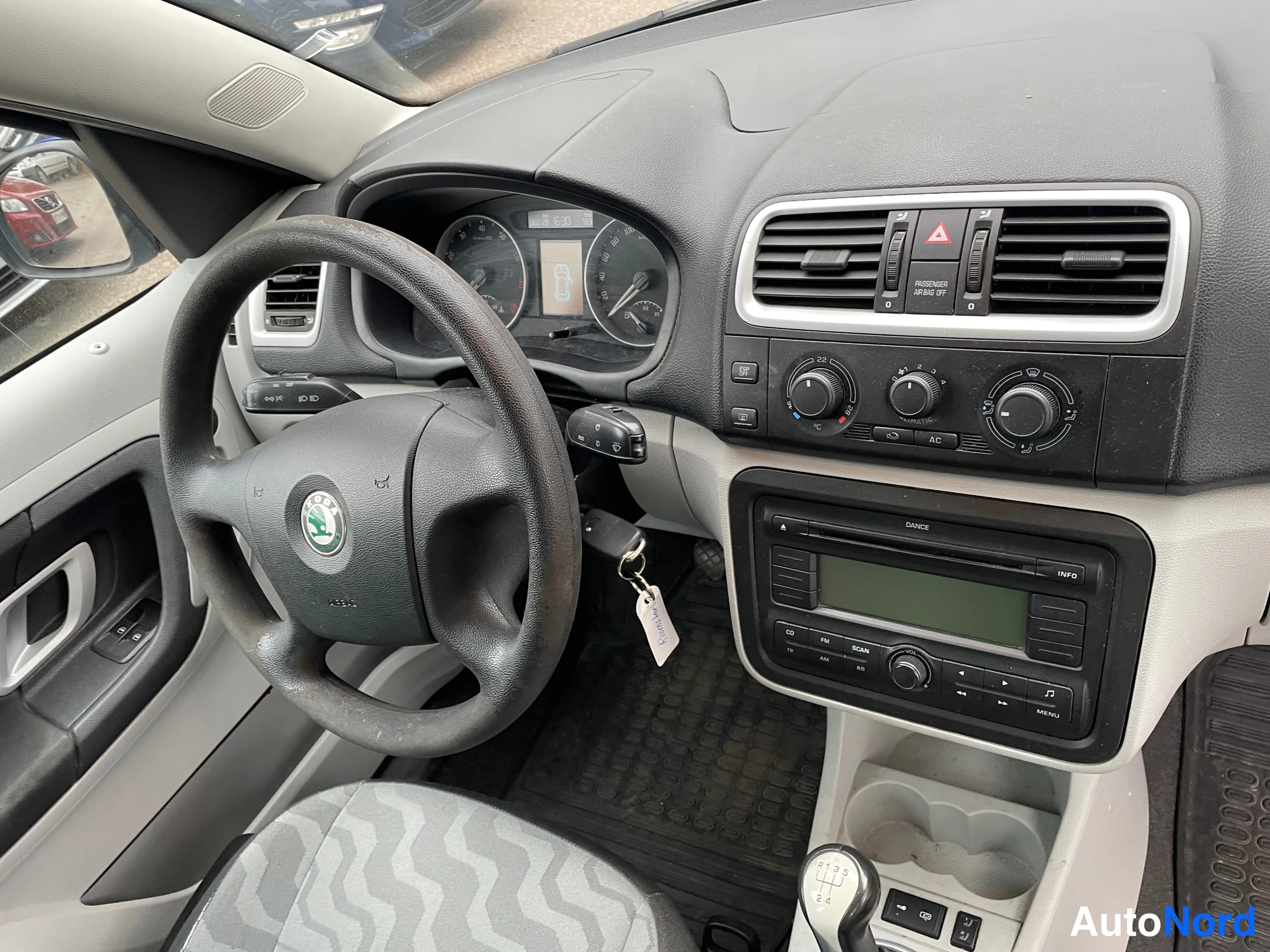 Sivulta: Kojelauta ja ohjaamo Skoda-merkillä: tietovirtamittaristo, ilmastointia säätävät nupit, radio (DANCE) ja vaihteenkeksi keskellä. Jarrukahva ja istuin osin näkyv