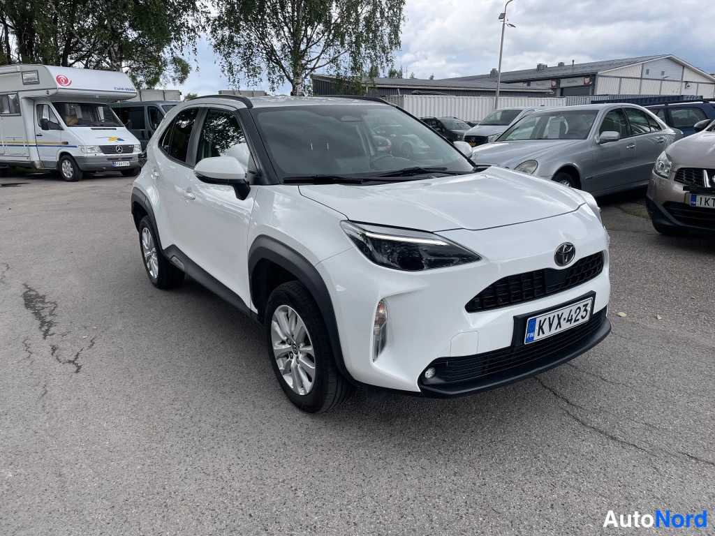 Etuviisto, nokka oikealle: Valkoinen Toyota Yaris Cross -henkilöauto kuvattu kolmivartalosta edestä oikealta, rekisterikilpi.