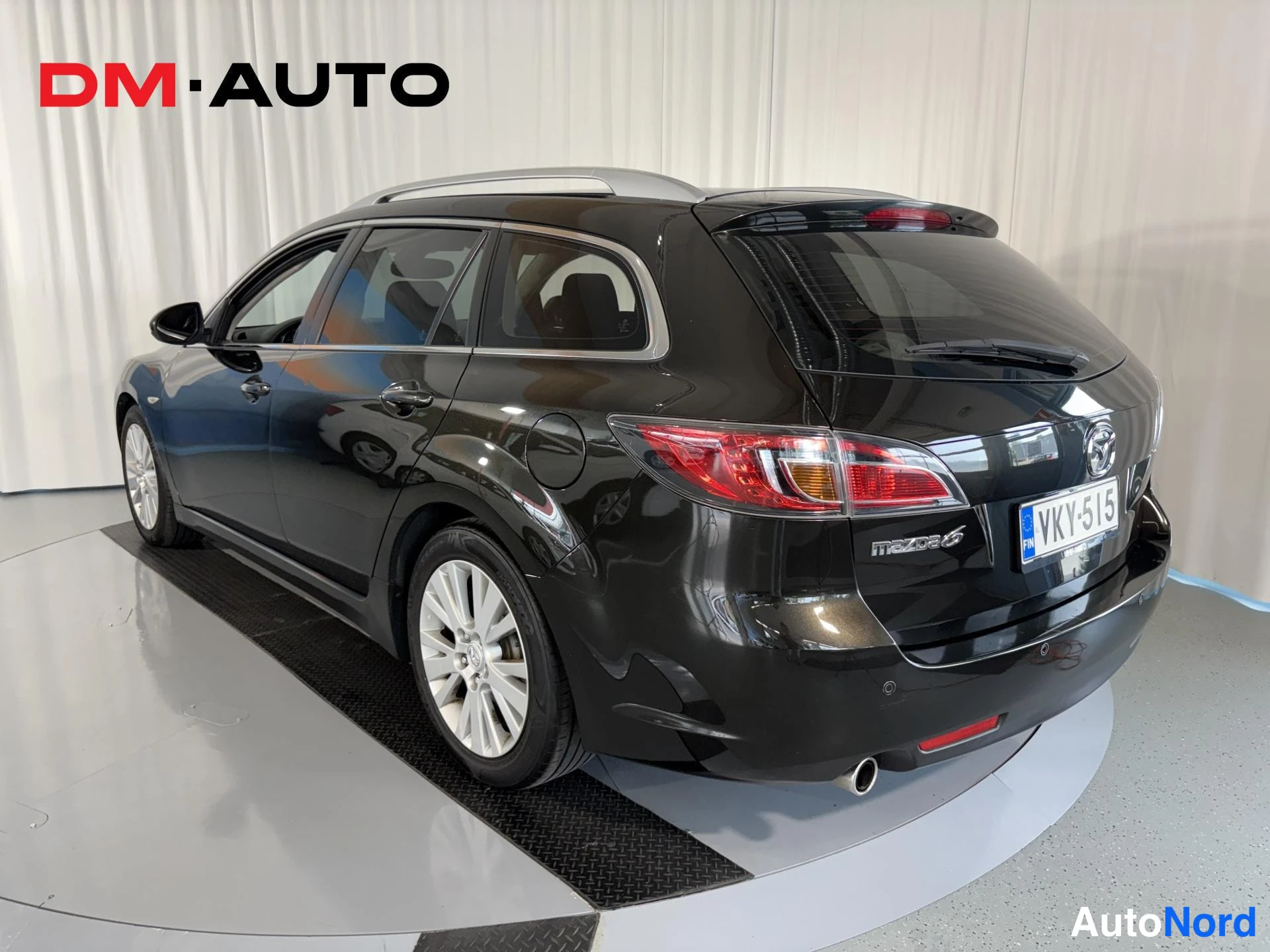 Takaviisto: Mustan farmariauton takaosa kolmeneljänneskulmasta vasemmalta, takavalo, Mazda 6 -merkintä ja rekisterikilpi.