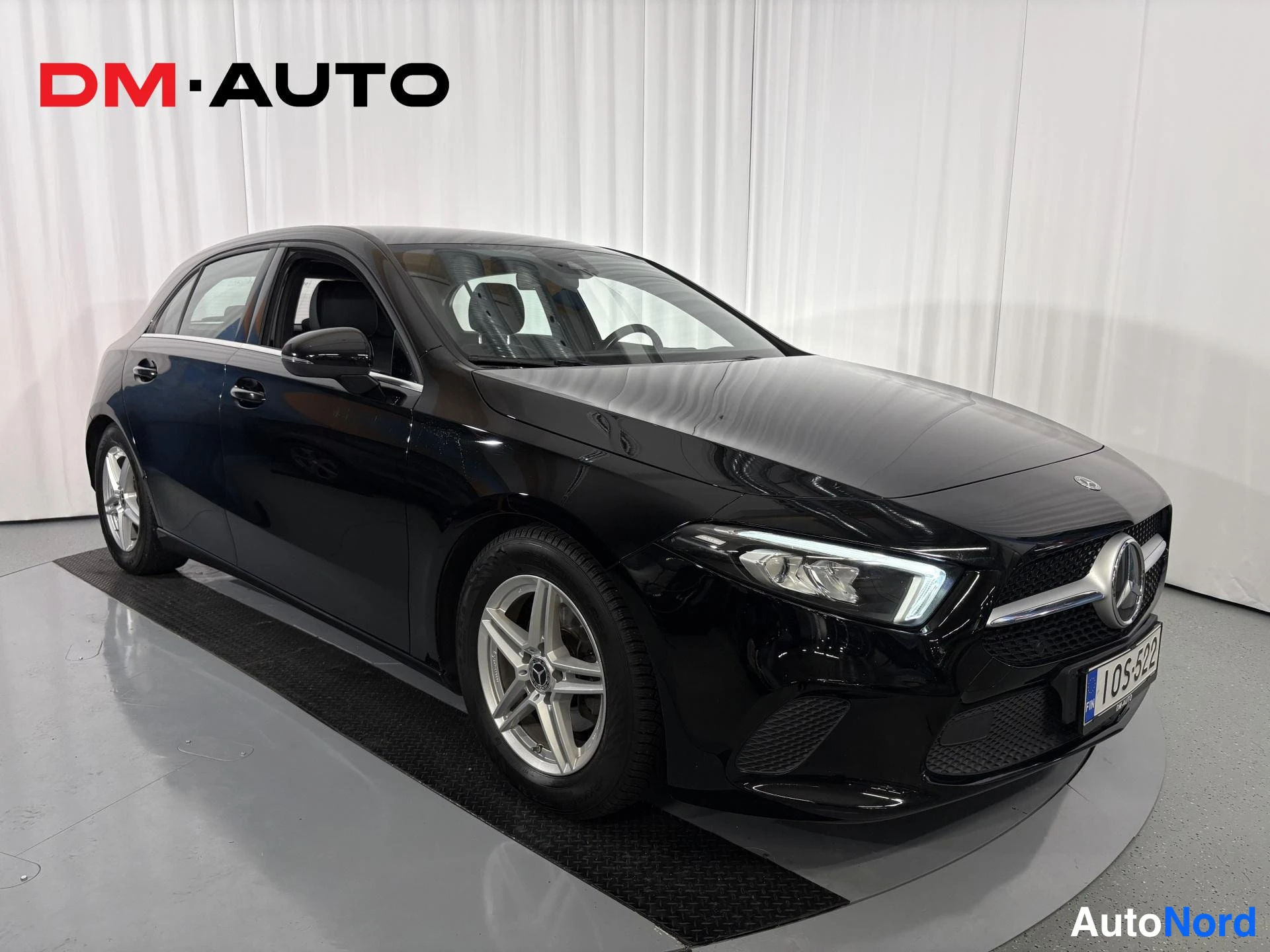 Etuviisto, nokka oikealle: Musta Mercedes-Benz henkilöauto kuvattu etuviistöstä oikealta; etupansa ja kylki näkyvät, viisivanteiset kevytmetallivanteet ja rekisterikilpi 1OS-522.