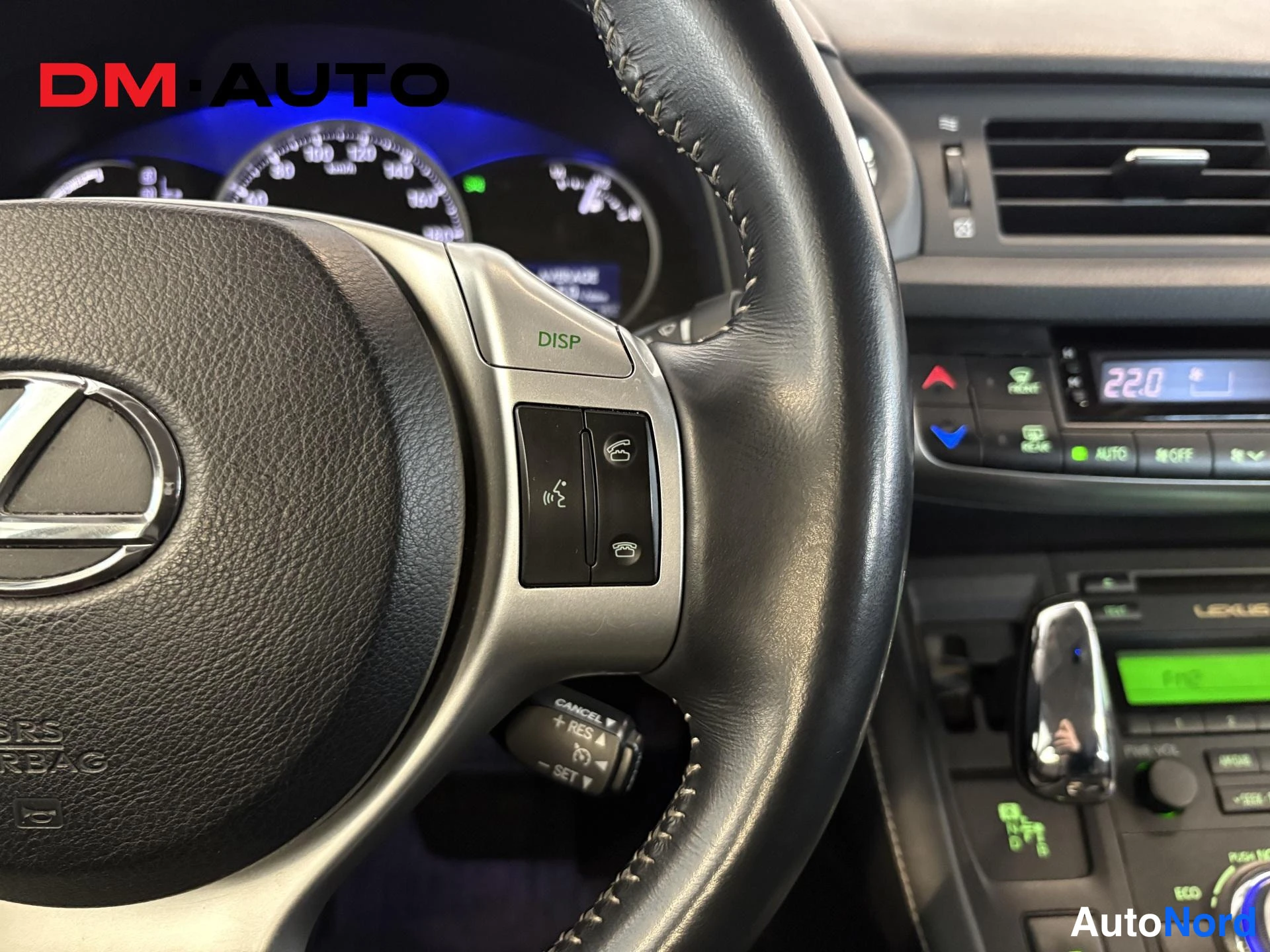 Muu: Ohjauspyörän ja kojelaudan lähikuva; ratissa Lexus-merkki, DISP-näppäin ja puhelin/puheaikataulun hallintanapit, taustalla mittaristo ja infotainment-näyttö.