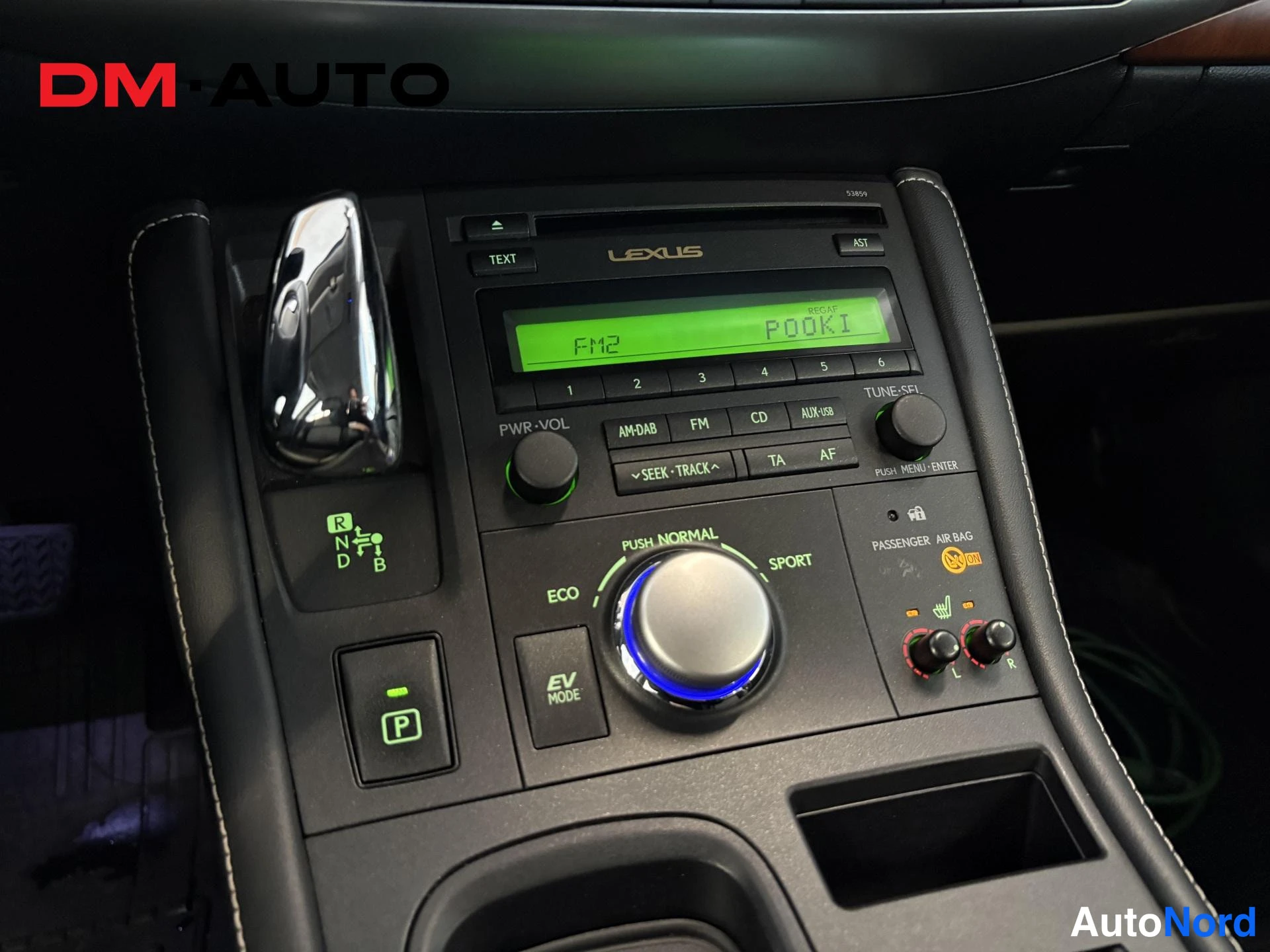 Muu: Keskihoidikon lähikuva: Lexus-radio vihreällä näytöllä (FM2 POOKI), AM/DAB, FM, CD ja AUX/USB -painikkeet, vaihteen kohdan näyttö (R N D B), ajotilakytkimet ECO