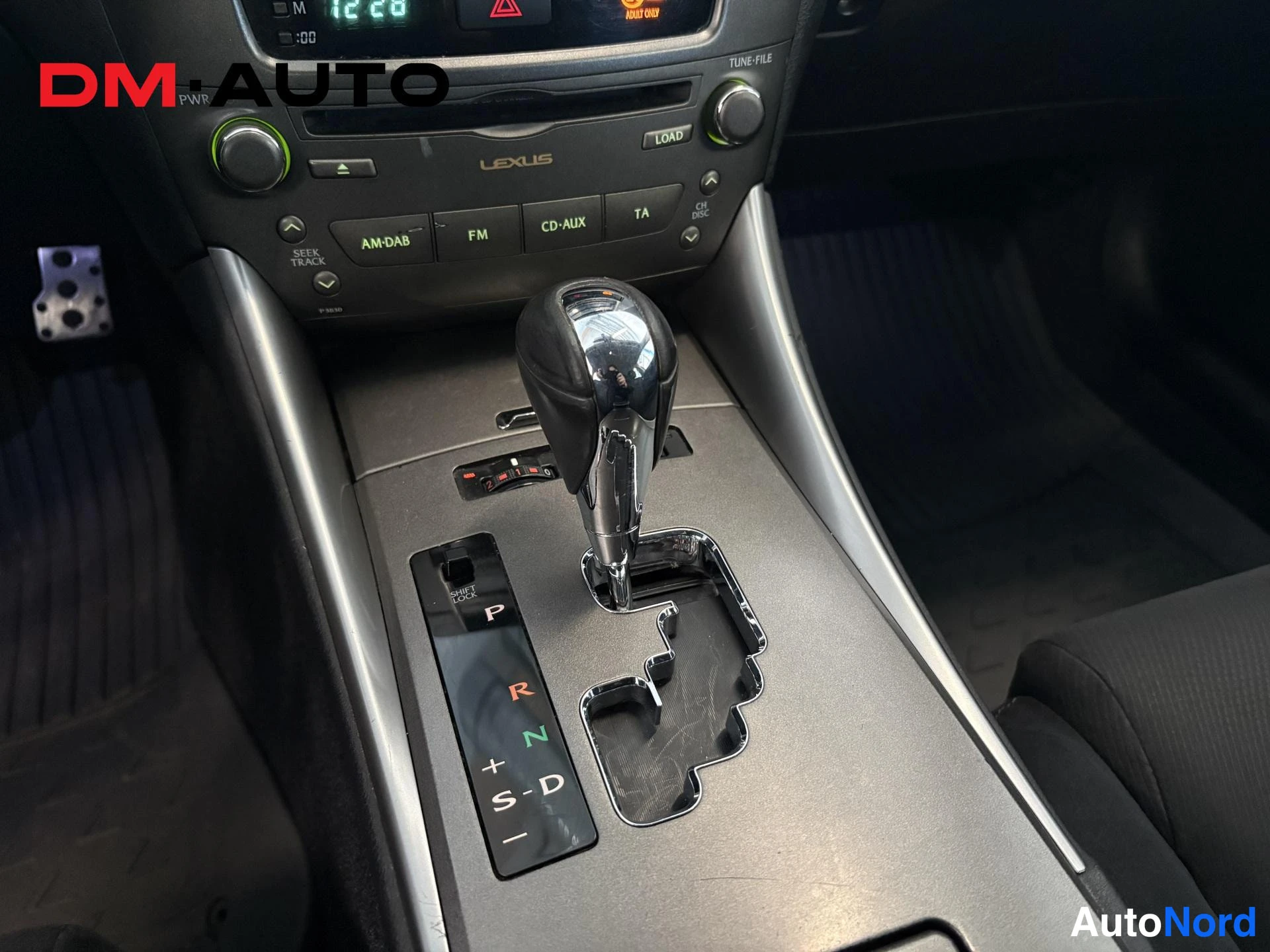 Muu: Vaihtokahvan ja keskiössä olevan automaattivaihteiston (P R N D S-D) lähikuva, taustalla Lexus-radion paneeli.