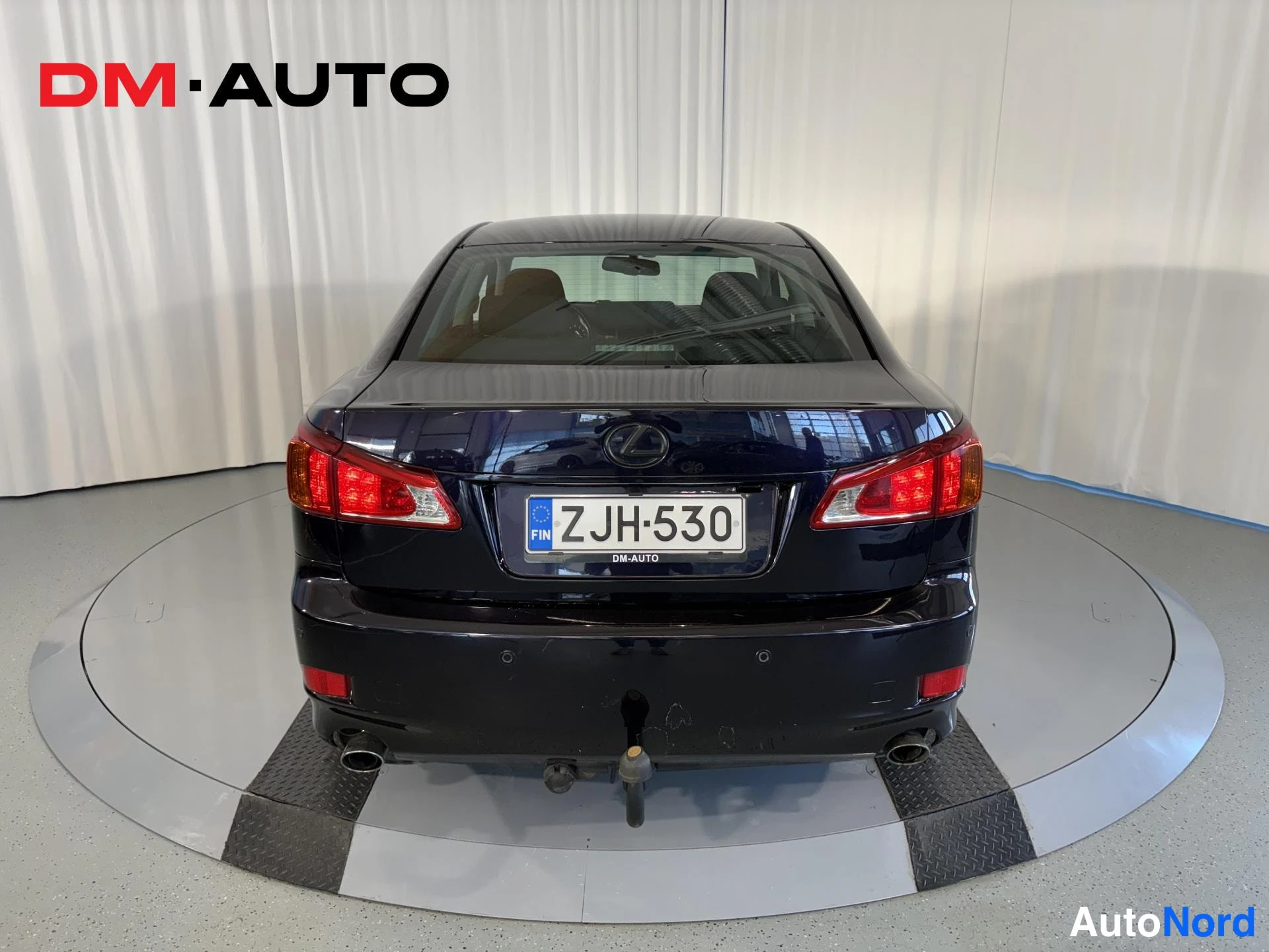Takaa: Auton takaosa suoraan takaa; rekisteri, Lexus-merkki takaluukussa, kaksi pakoputkea ja vedettävä vetokoukku näkyvät.