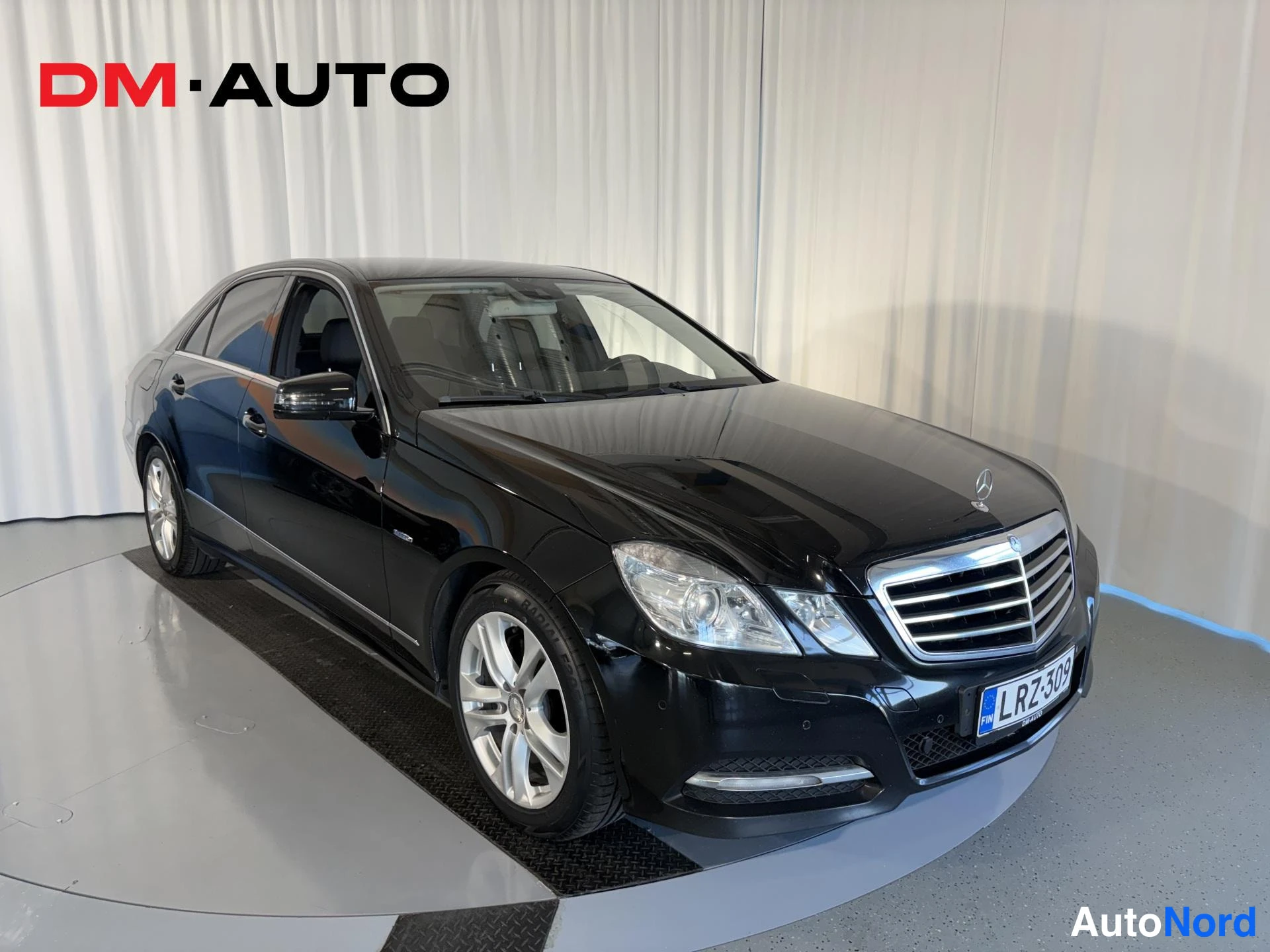 Etuviisto, nokka oikealle: Musta Mercedes-Benz E-sarjan sedan, etukolmanneluva oikealta, rekisteri, studio-kuva.