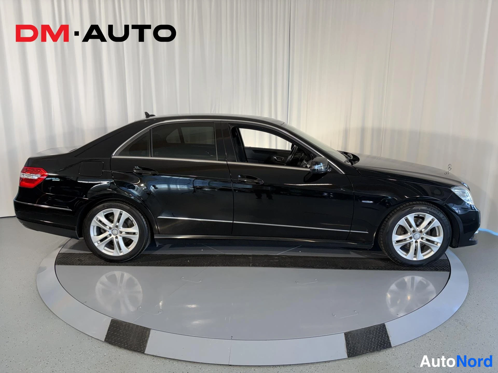 Takaviisto: Musta Mercedes-Benz E-sarjan sedan, takaoksakuva vasemmalta, rekisteritunnus, studio-kuva.