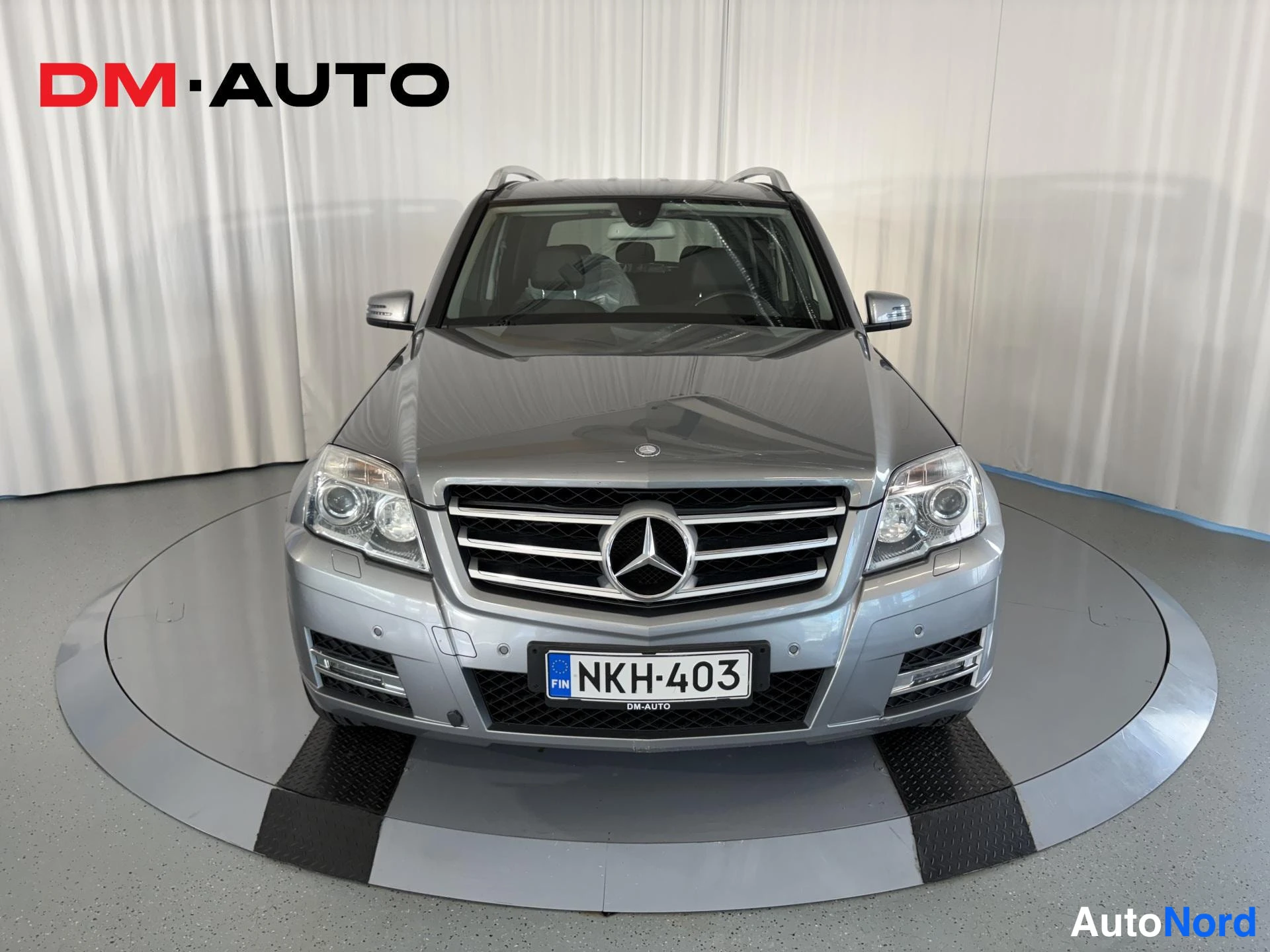 Edestä: Hopeanharmaa Mercedes-Benz GLK suoraan edestä kuvattuna, etusäleikkö ja rekisterikilpi näkyvät.