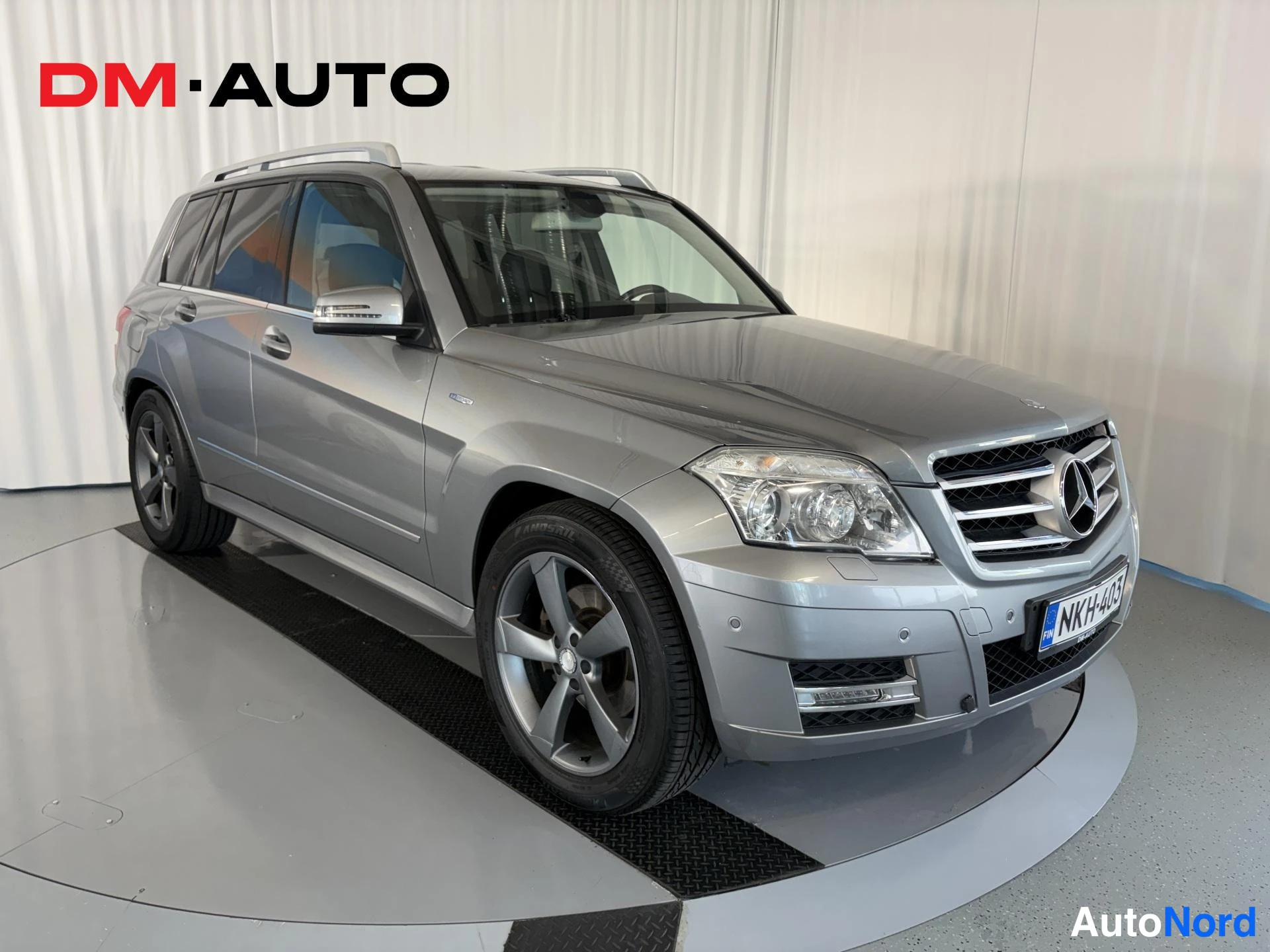 Etuviisto, nokka oikealle: Hopeanharmaa Mercedes-Benz GLK:n etukulmanäyttö oikealta sisätiloissa, rekisterikilpi näkyy.