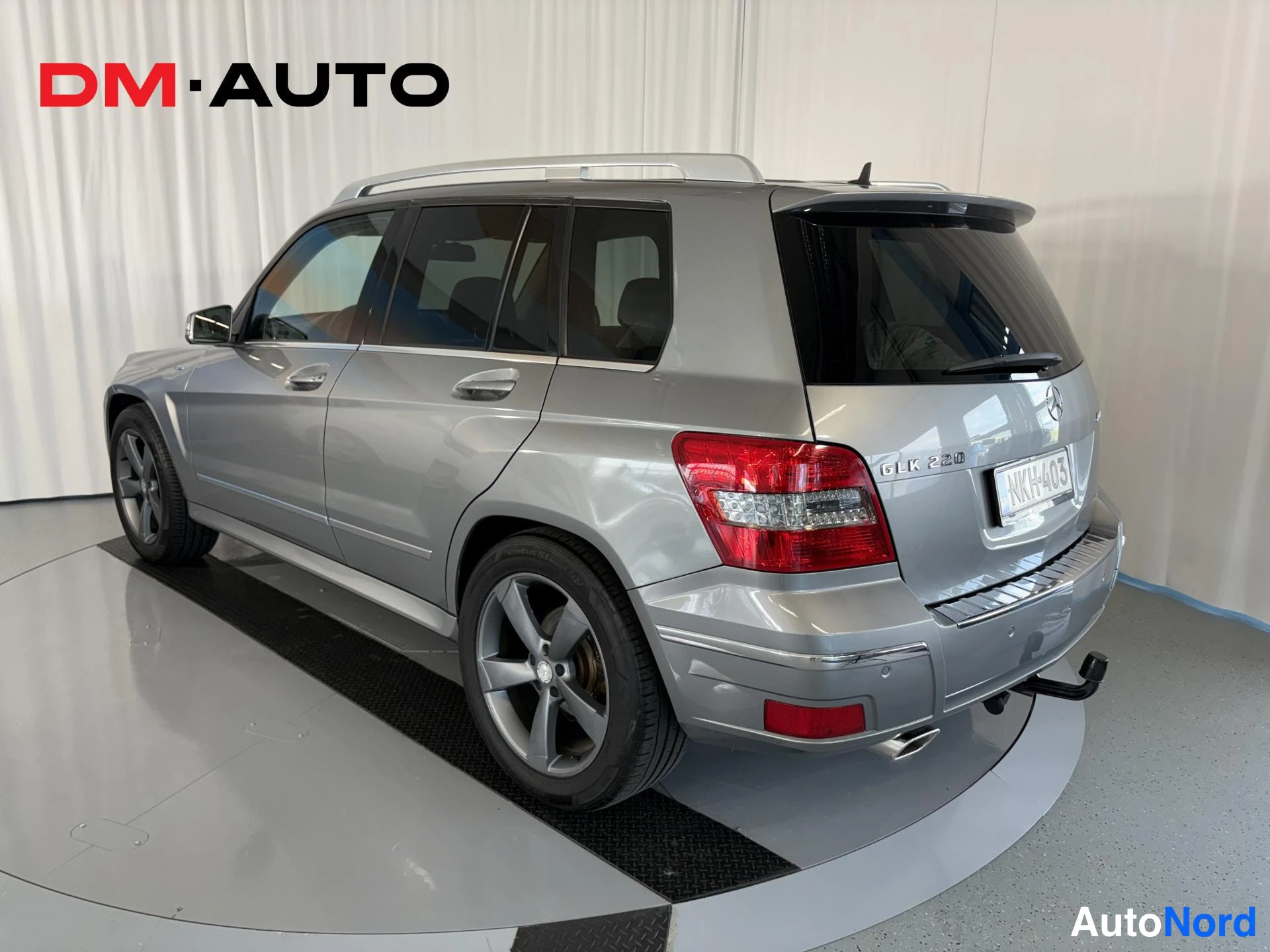 Takaviisto: Hopeanharmaa Mercedes-Benz GLK takaa sivulta kuvattuna, rekisteritunnus, GLK 220 -merkintä ja vetokoukku näkyvissä.