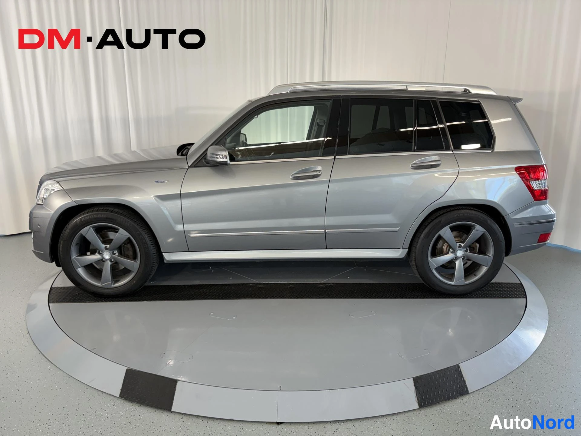 Sivulta: Hopeanharmaa Mercedes-Benz GLK sivulta kuvattuna, kattokaiteet, kromilistat ja kevytmetallivanteet näkyvissä.