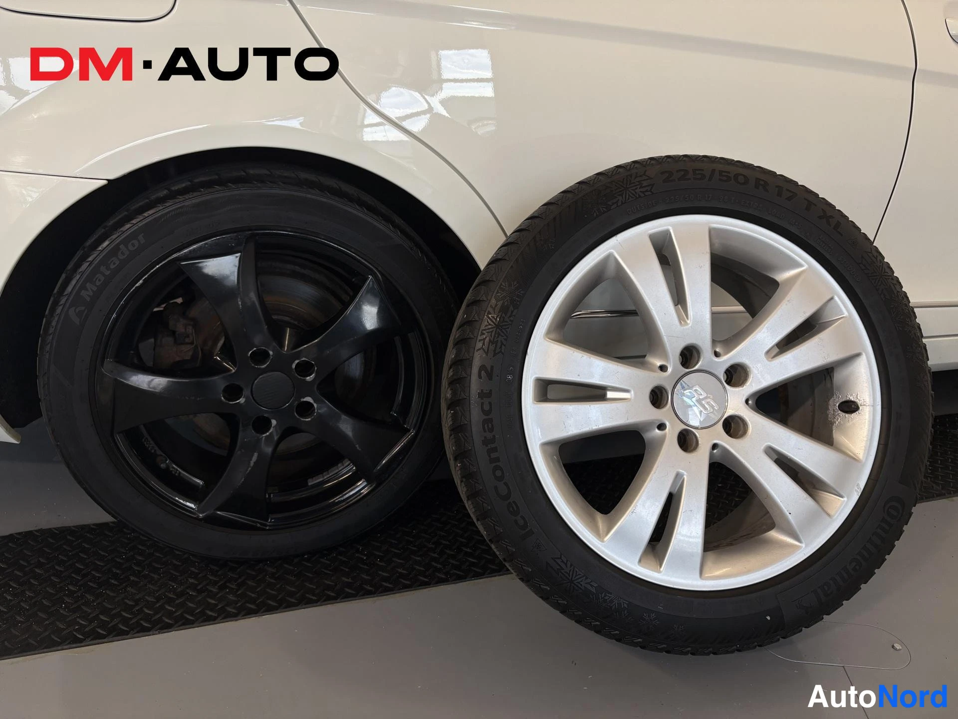 Muu: Auton musta rengas napassa sekä vieressä irtonainen hopeavanne rengas, Continental IceContact 2, 225/50 R 17.