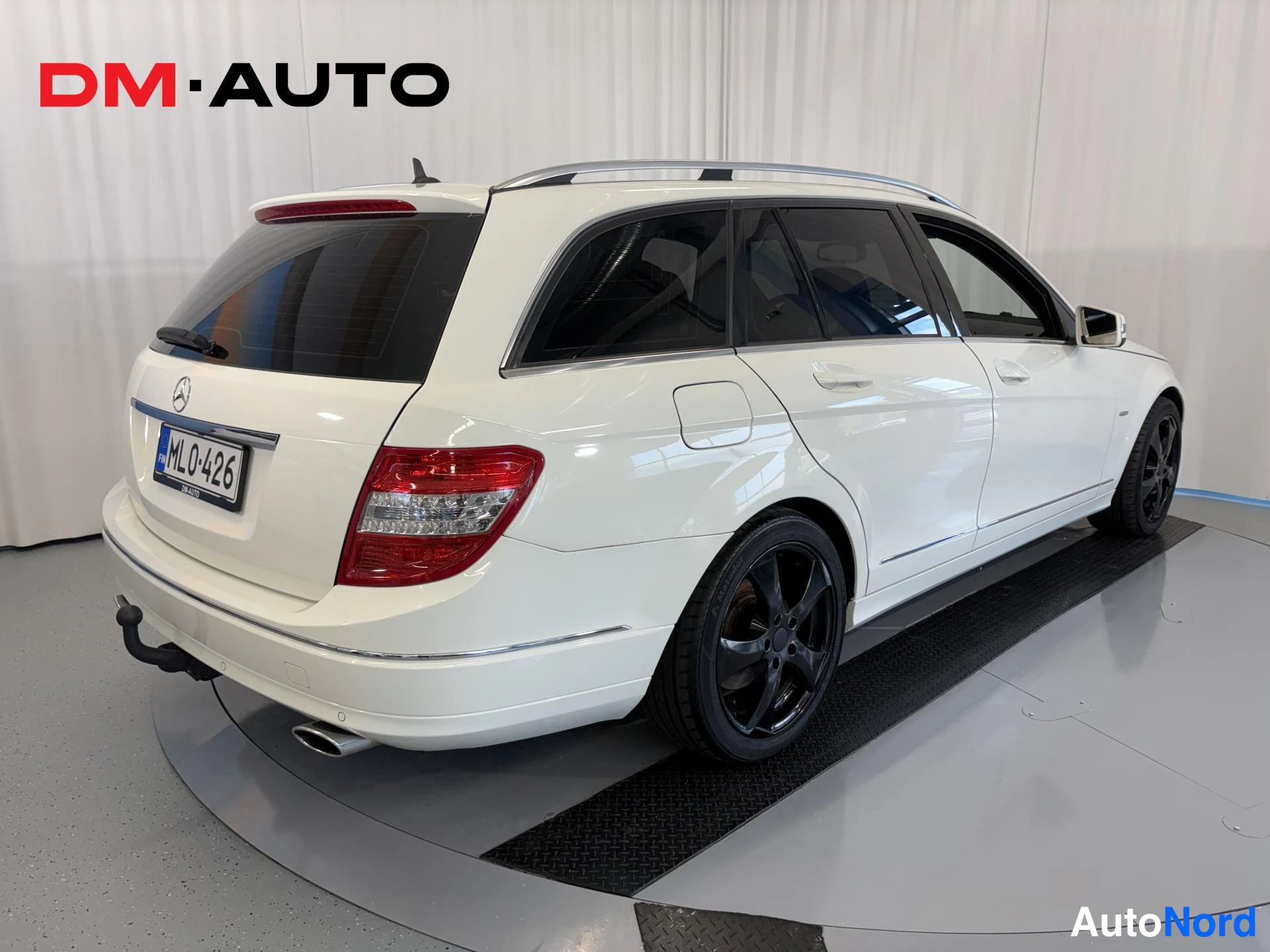 Takaviisto: Mercedes-Benz C-sarjan farmaritakin valkoisena takaa viistosti vasemmalta, mustat vanteet ja katolla kromikaiteet.