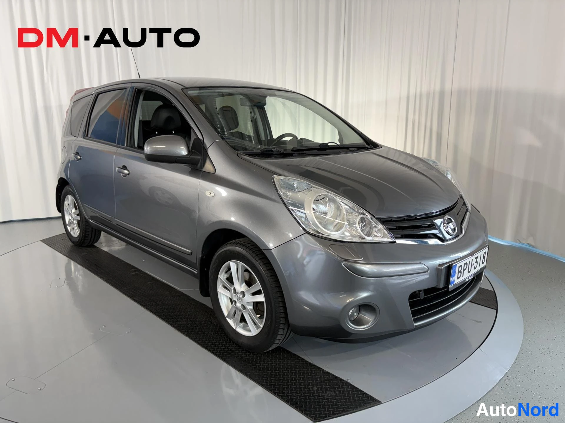 Etuviisto, nokka oikealle: Nissan Note, etunurkkakuva oikealta, tummanharmaa