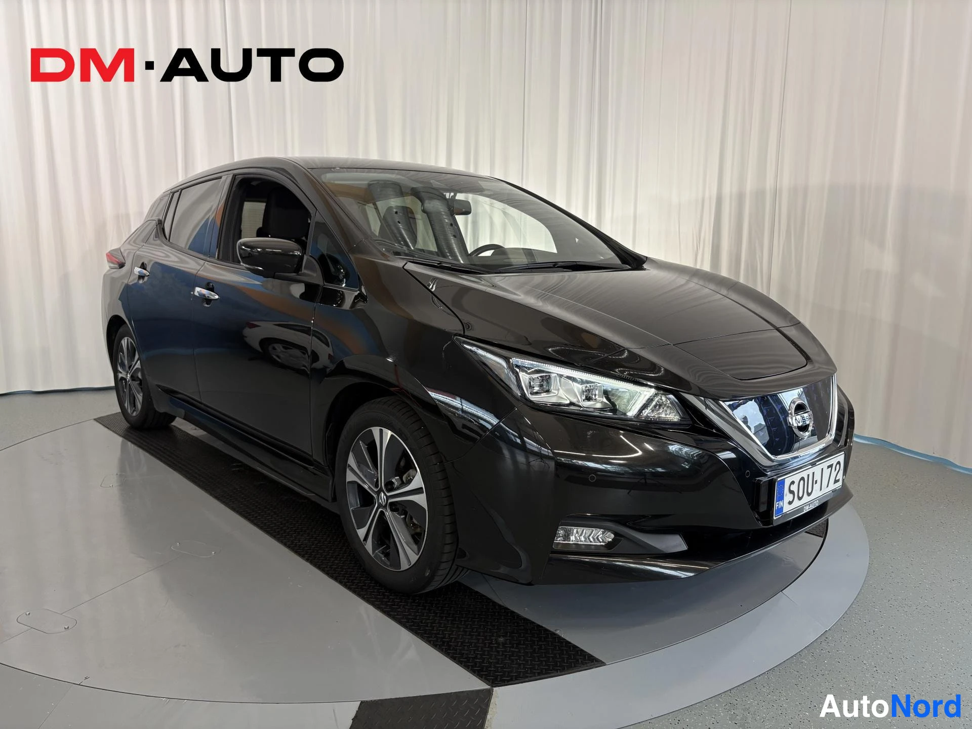 Etuviisto, nokka oikealle: Mustan Nissan Leafin etunurkkaus oikealta edestä, rekisterikilpi.