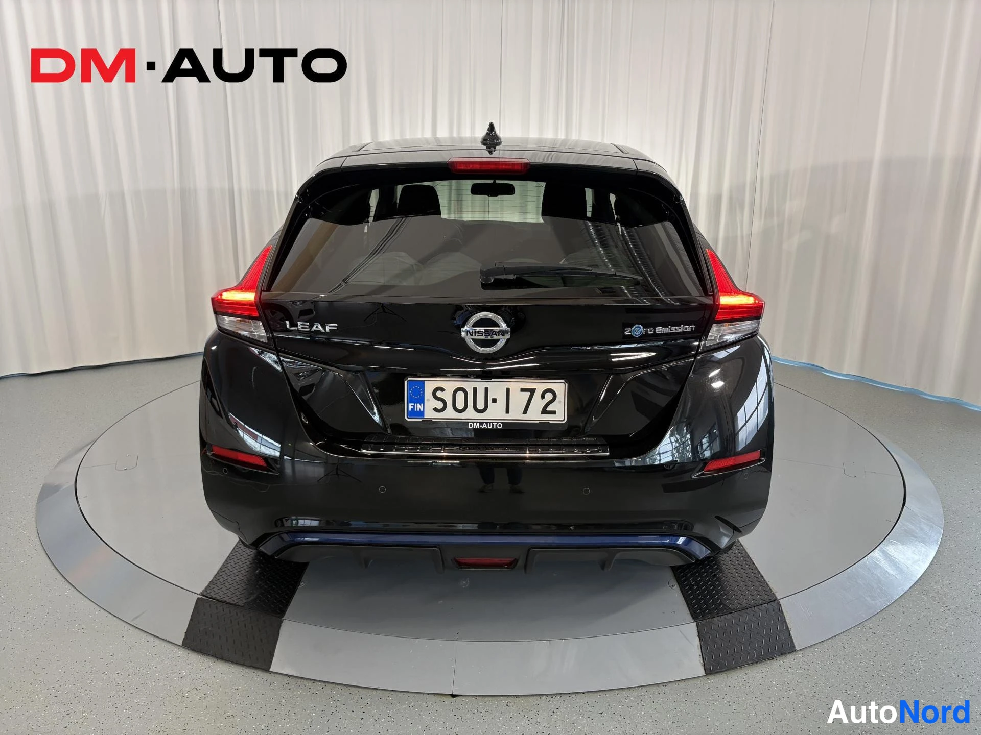 Takaa: Musta Nissan Leaf suoraan takaa, LEAF- ja Zero Emission -tekstit sekä rekisterikilpi näkyvissä.