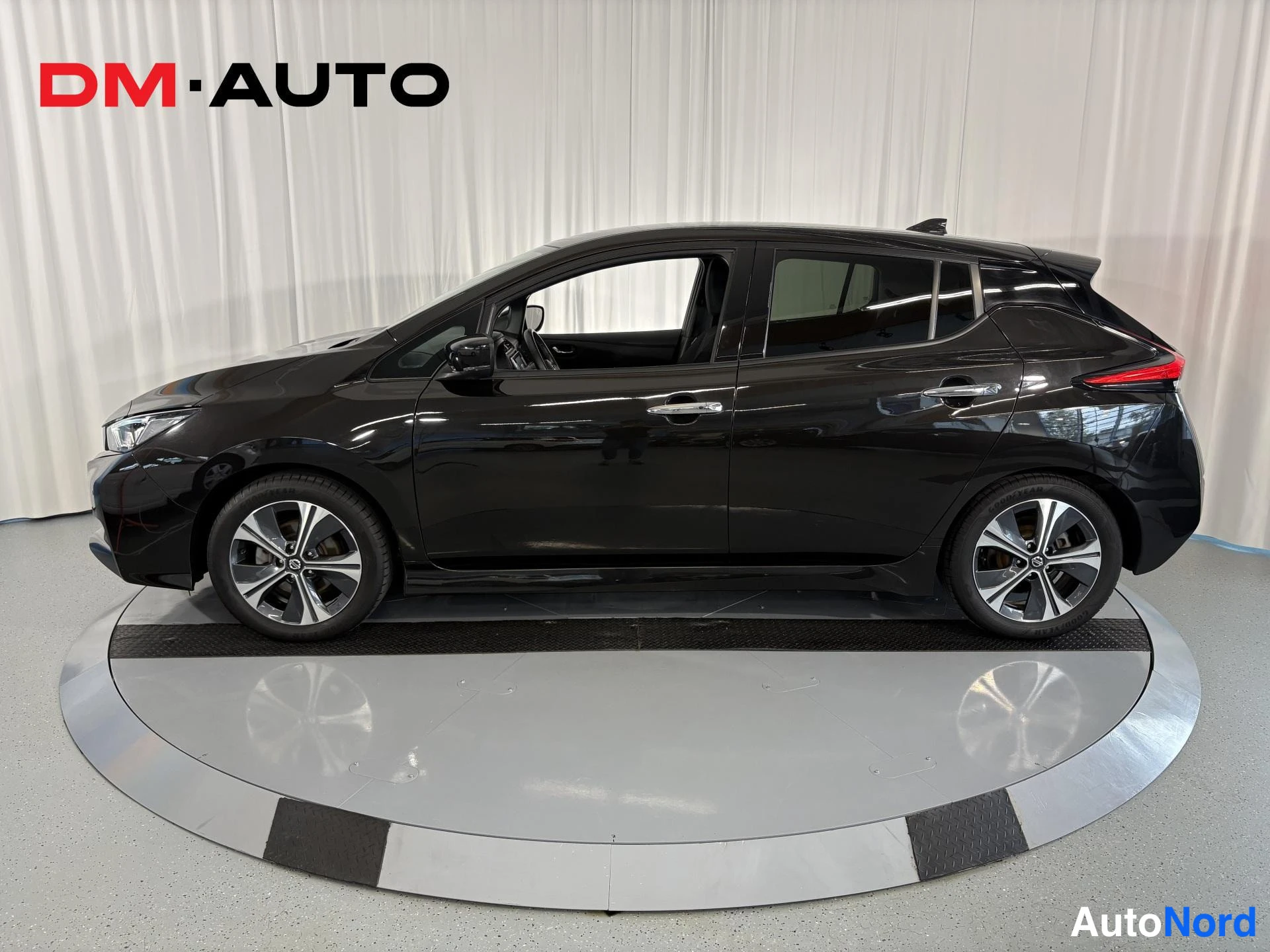 Sivulta: Musta Nissan Leaf kokonaan sivulta, kyljen ovet ja ikkunat näkyvissä.