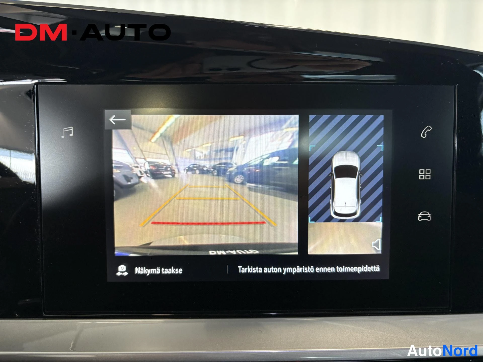 Muu: Infotainment-näytön takaosan kamera- ja ympäristönäkymä, jossa luodaan pysäköintitilanne ja tekstit 'Näkymä taakse' ja 'Tarkista auton ympäristö ennen toimenpid