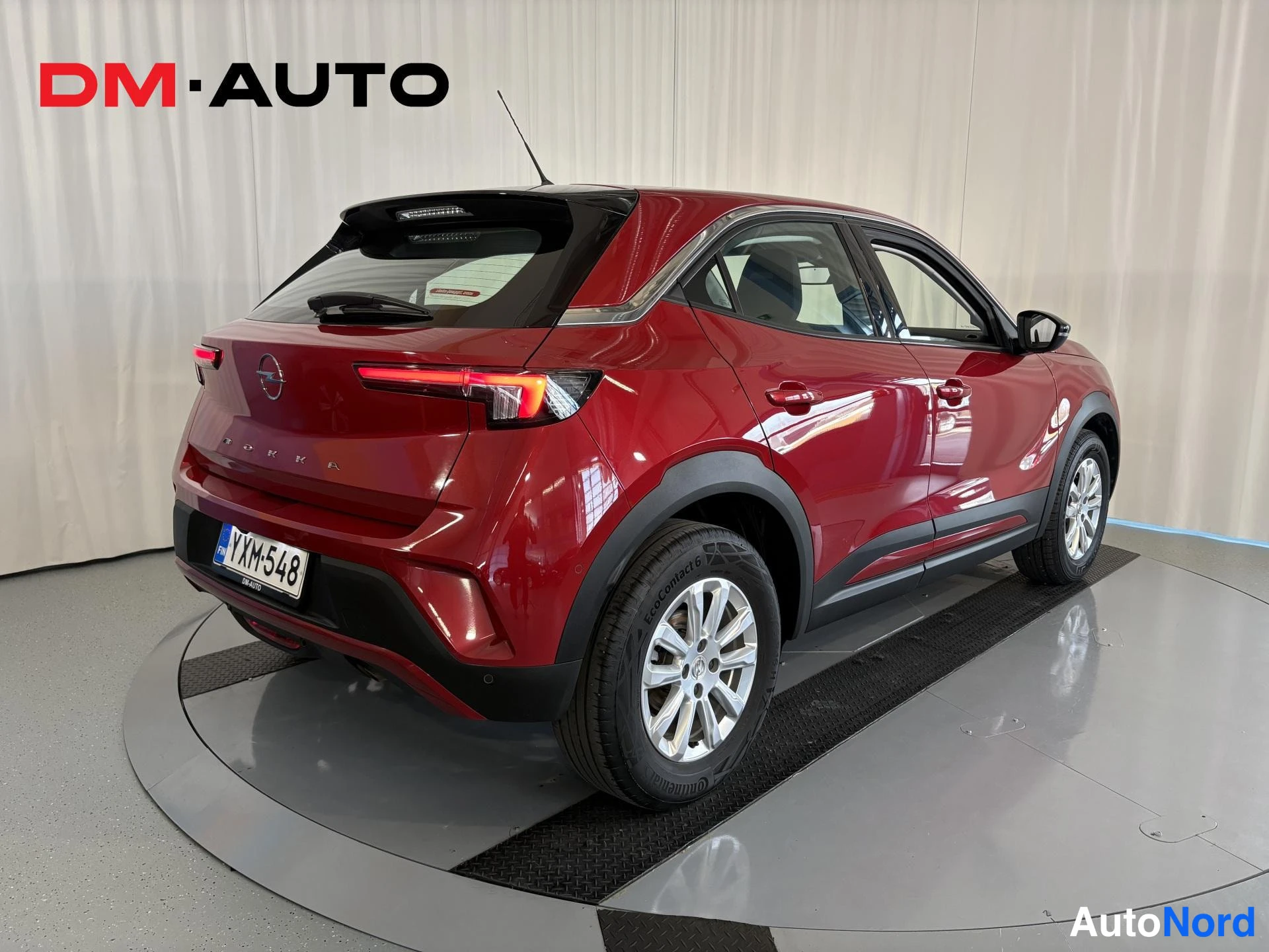 Takaviisto: Punaisen Opel Mokkan takanurkkaus, rekisterikilpi ja vaaleat kevytmetallivanteet studiokuvassa.