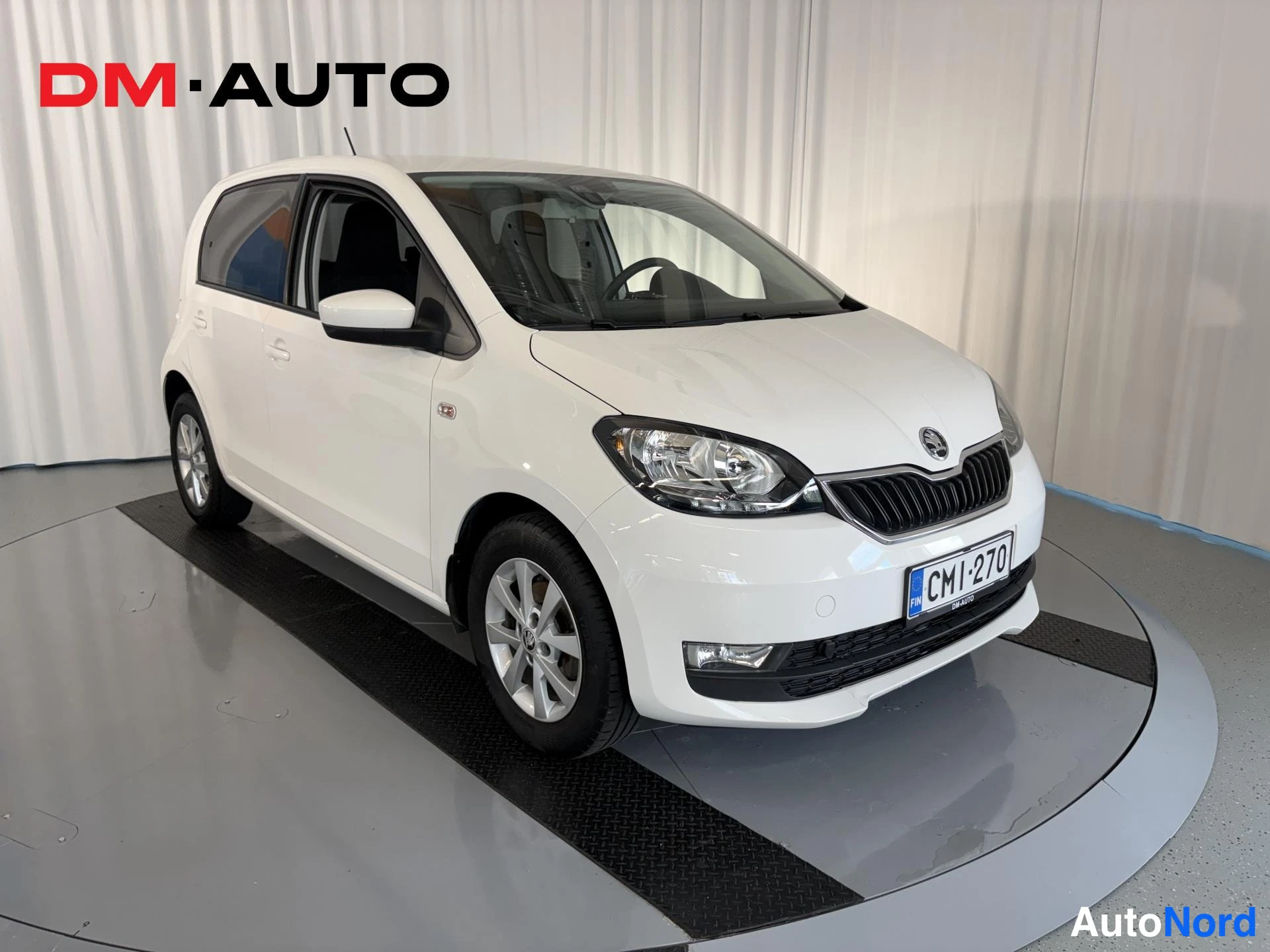 Etuviisto, nokka oikealle: Valkoinen Skoda Citigo viistosti edestä oikealta, etusäleikkö ja rekisterikilpi CM1-270 näkyvät.