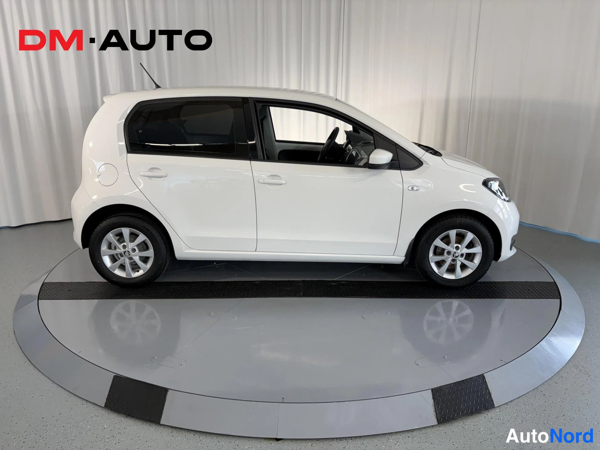 Sivulta: Valkoinen Skoda Citigo sivusta oikealta, neljä ovea ja molemmat pyörät näkyvät.