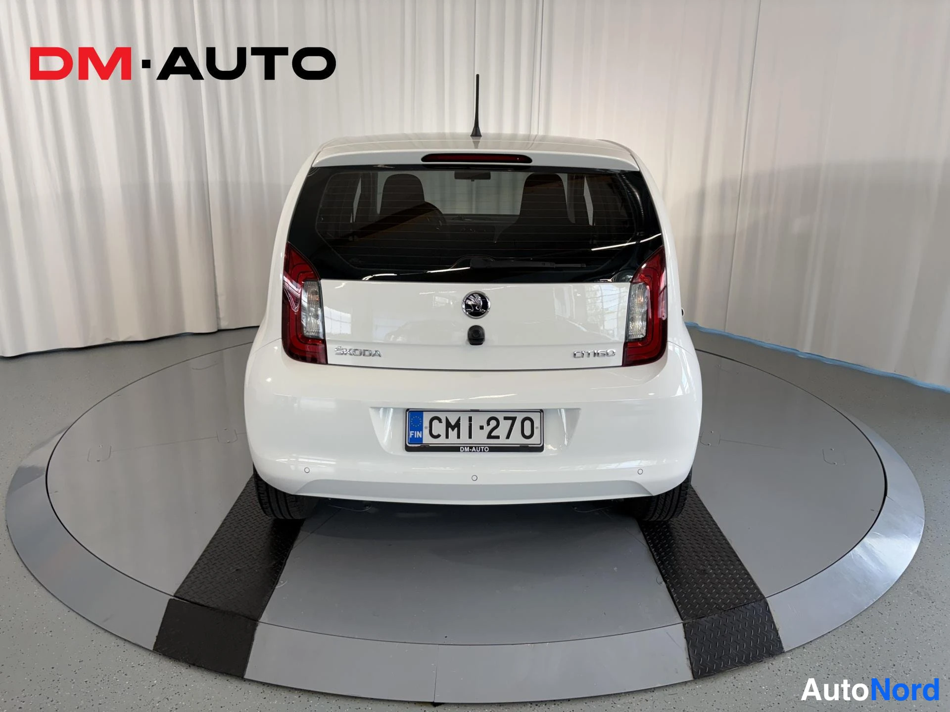 Takaa: Valkoisen tila-auton takaosa suoraan takaa; Skoda-logo, takavalo ja rekisterikilpi.