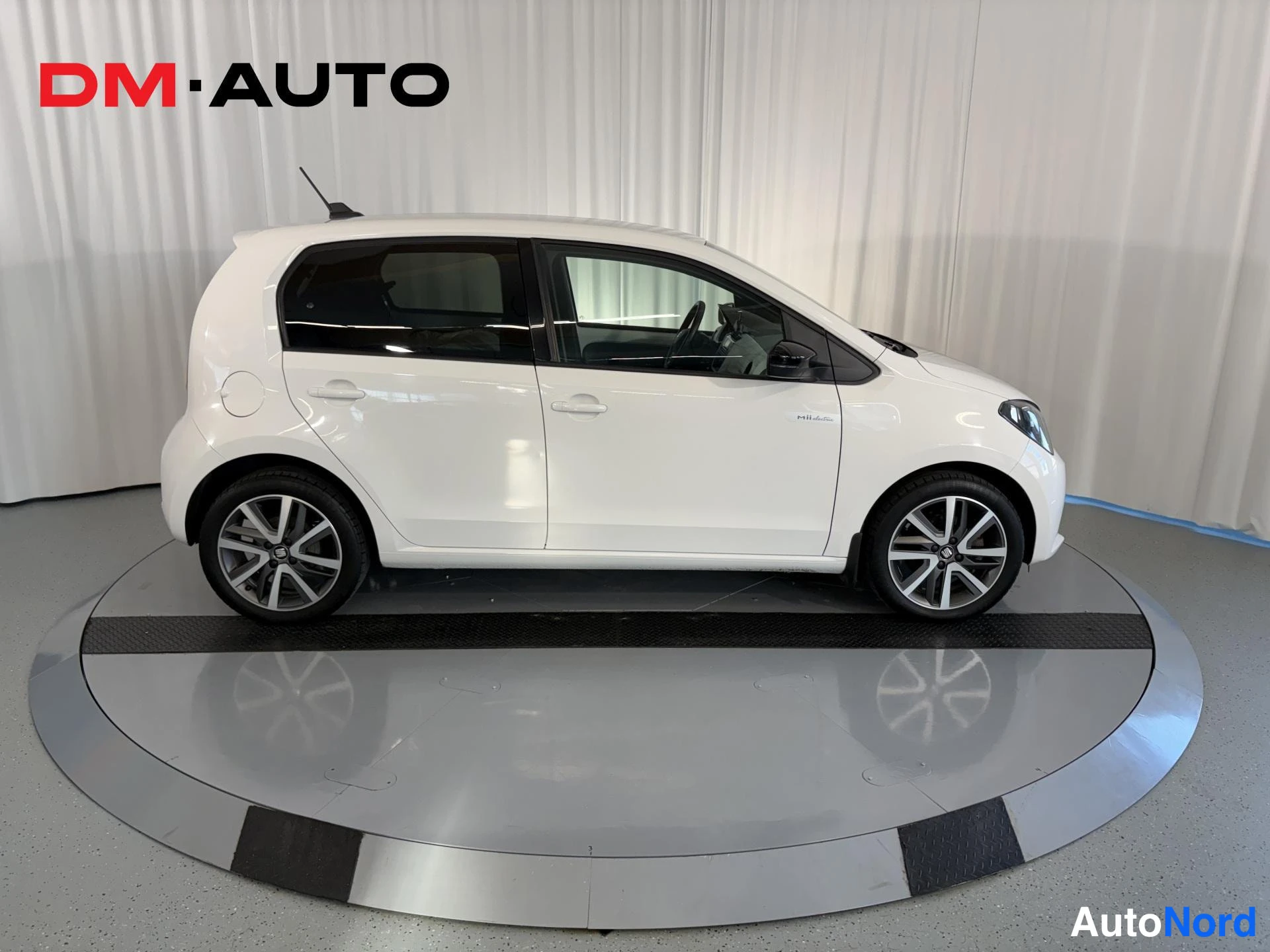 Sivulta: White SEAT Mii Electric photographed directly from the side: doors, windows, alloy wheels and black wing mirror are visible, front and rear faces out of frame.