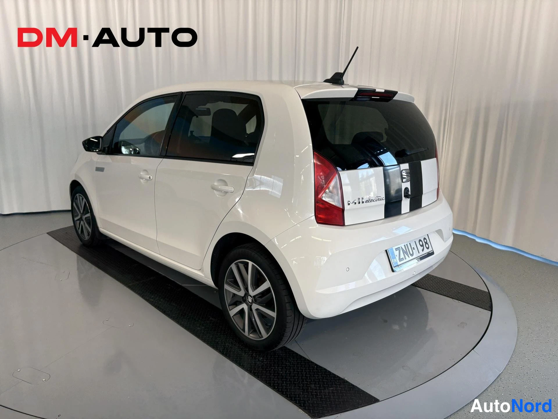 Takaviisto: Auton takakulma oikealta: valkoinen Seat Mii Electric, musta kilparaita, rekisteritunnus.